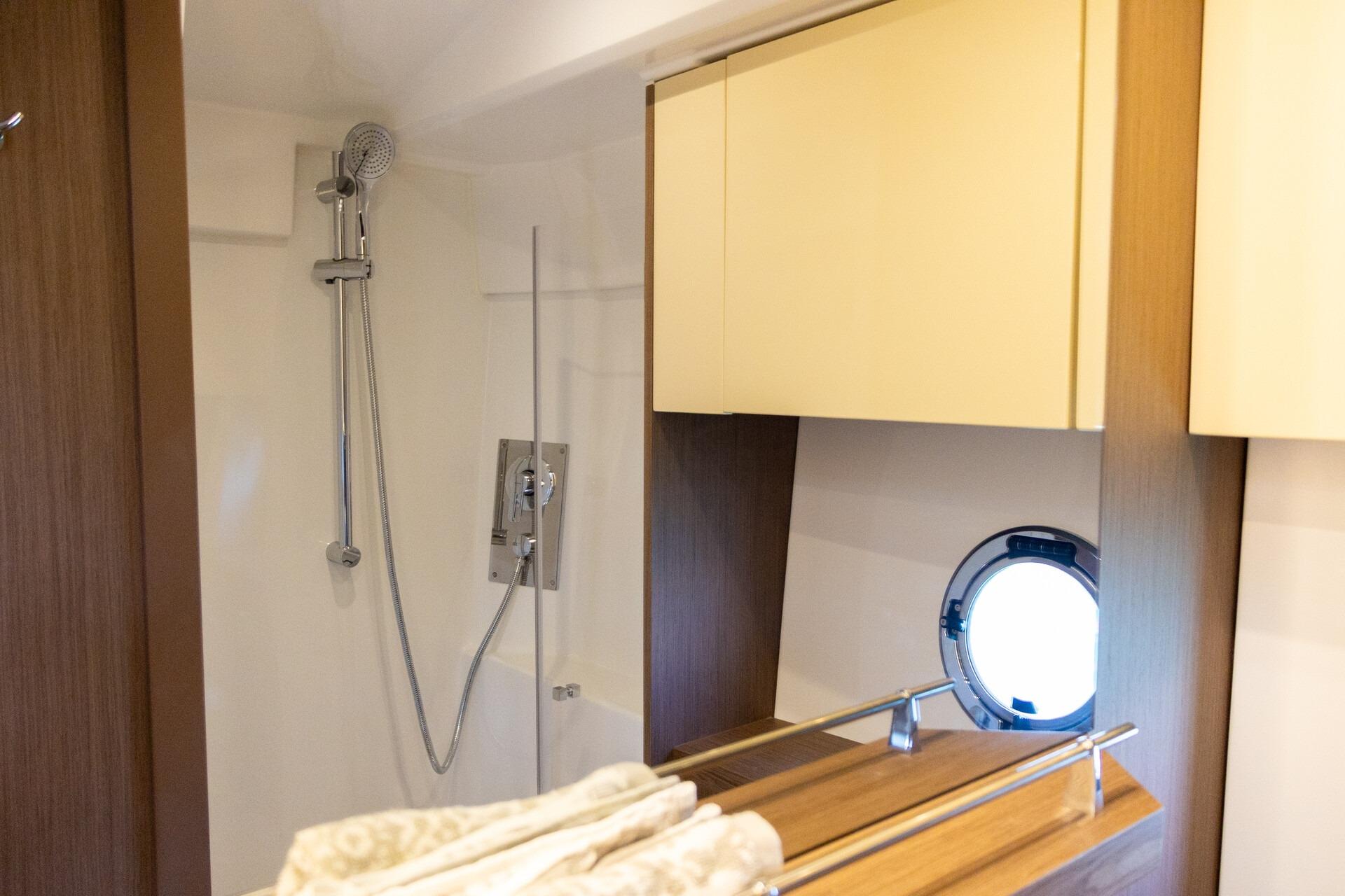 Luxurious bathroom interior of 2019 Beneteau Gran Turismo 46 yacht with shower and porthole.