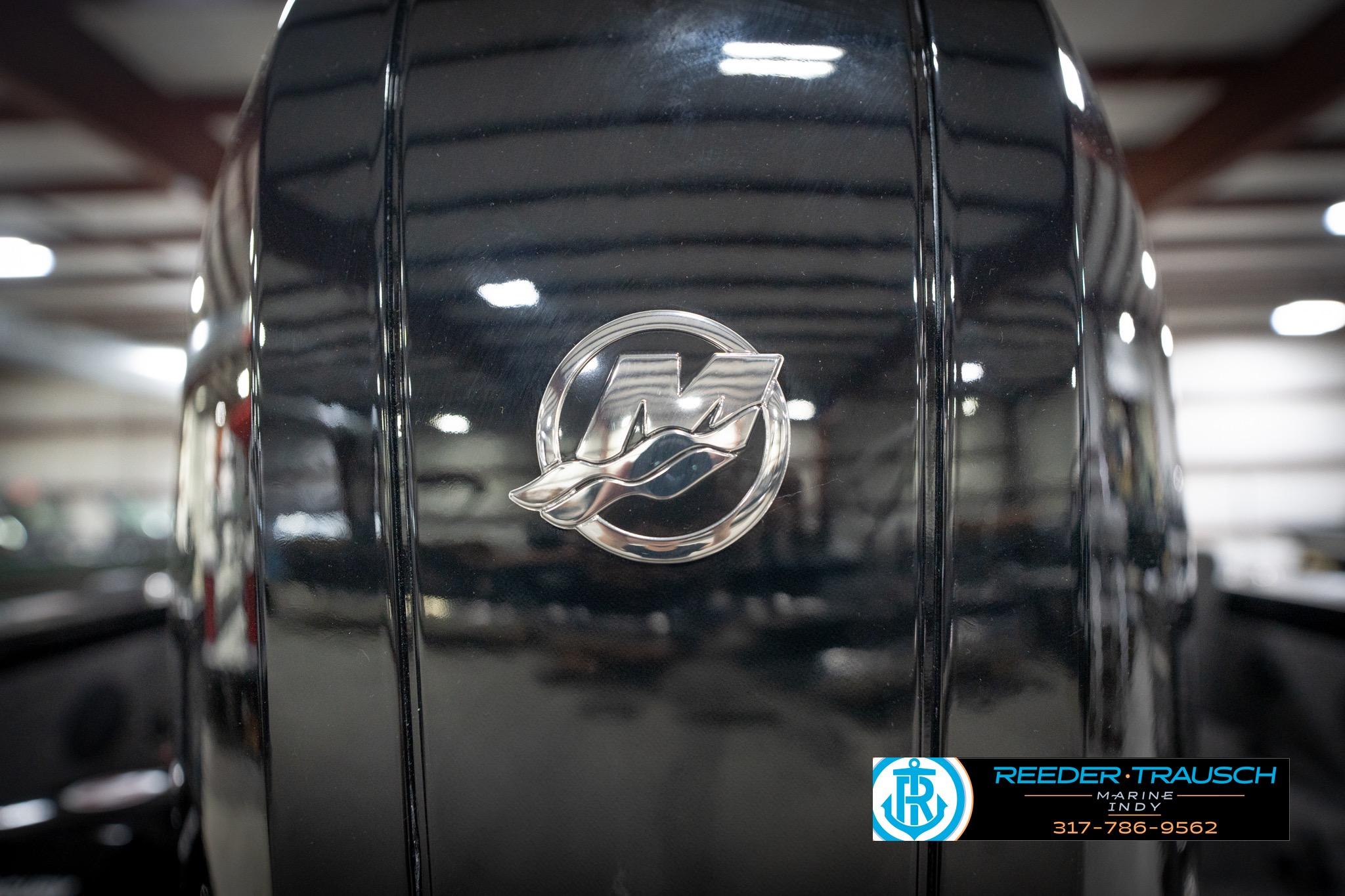 Close-up of 2026 Lund 2275 Baron boat engine with logo in a showroom.