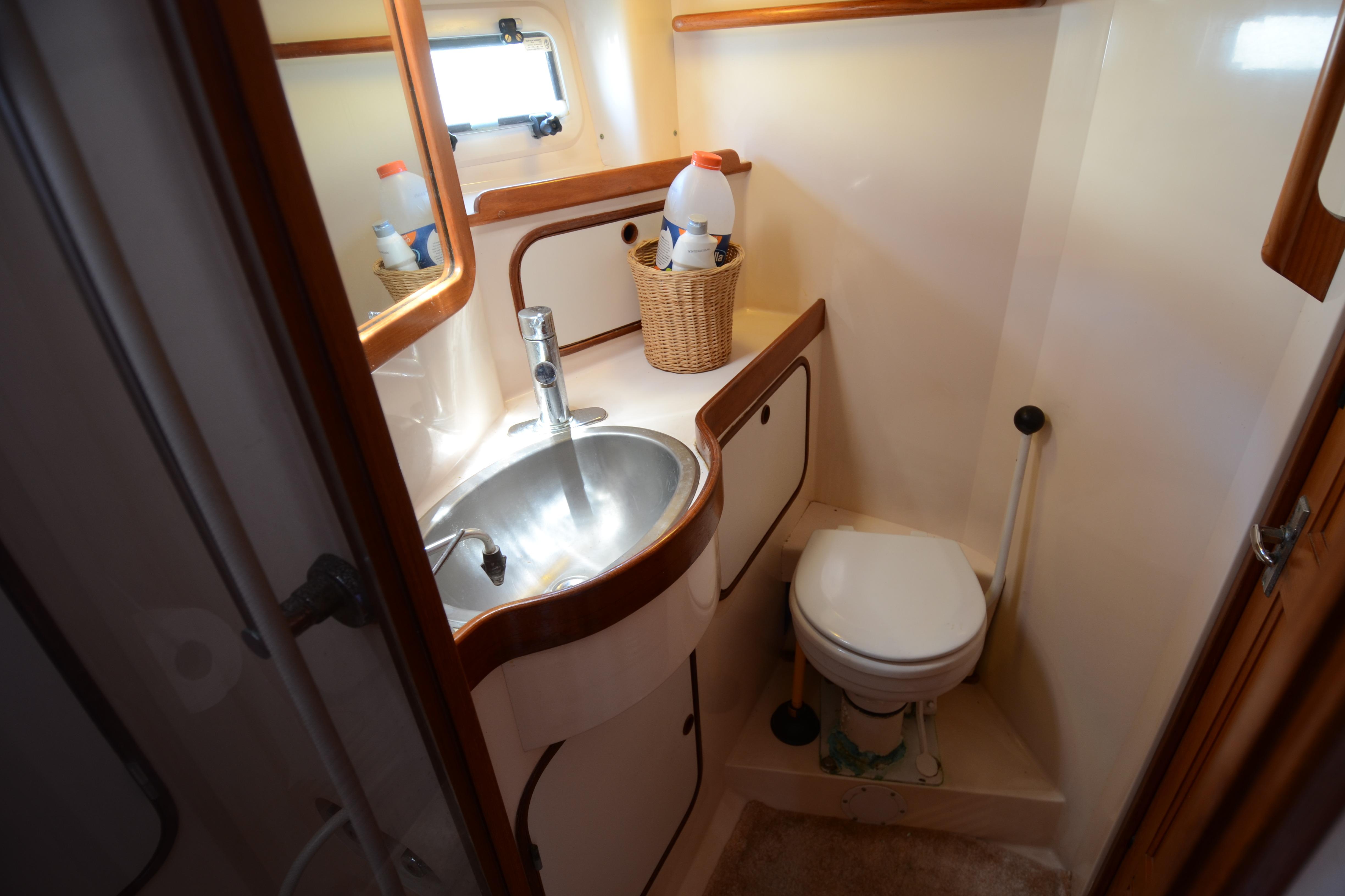 Compact bathroom in 1987 Norseman 400 yacht with sink, toilet, and storage basket.