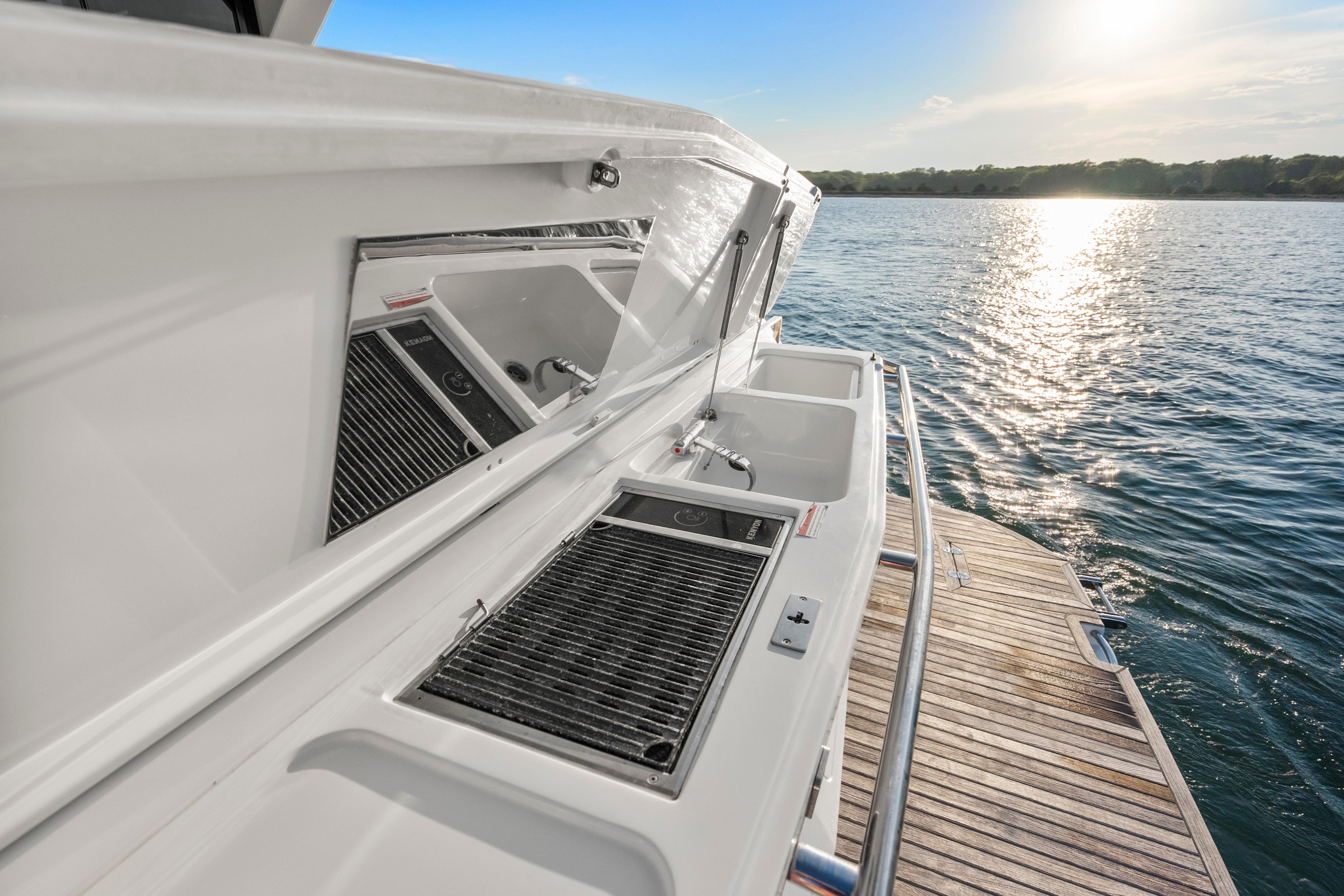 2023 Galeon 400 Fly yacht with outdoor kitchen, overlooking serene water at sunset.