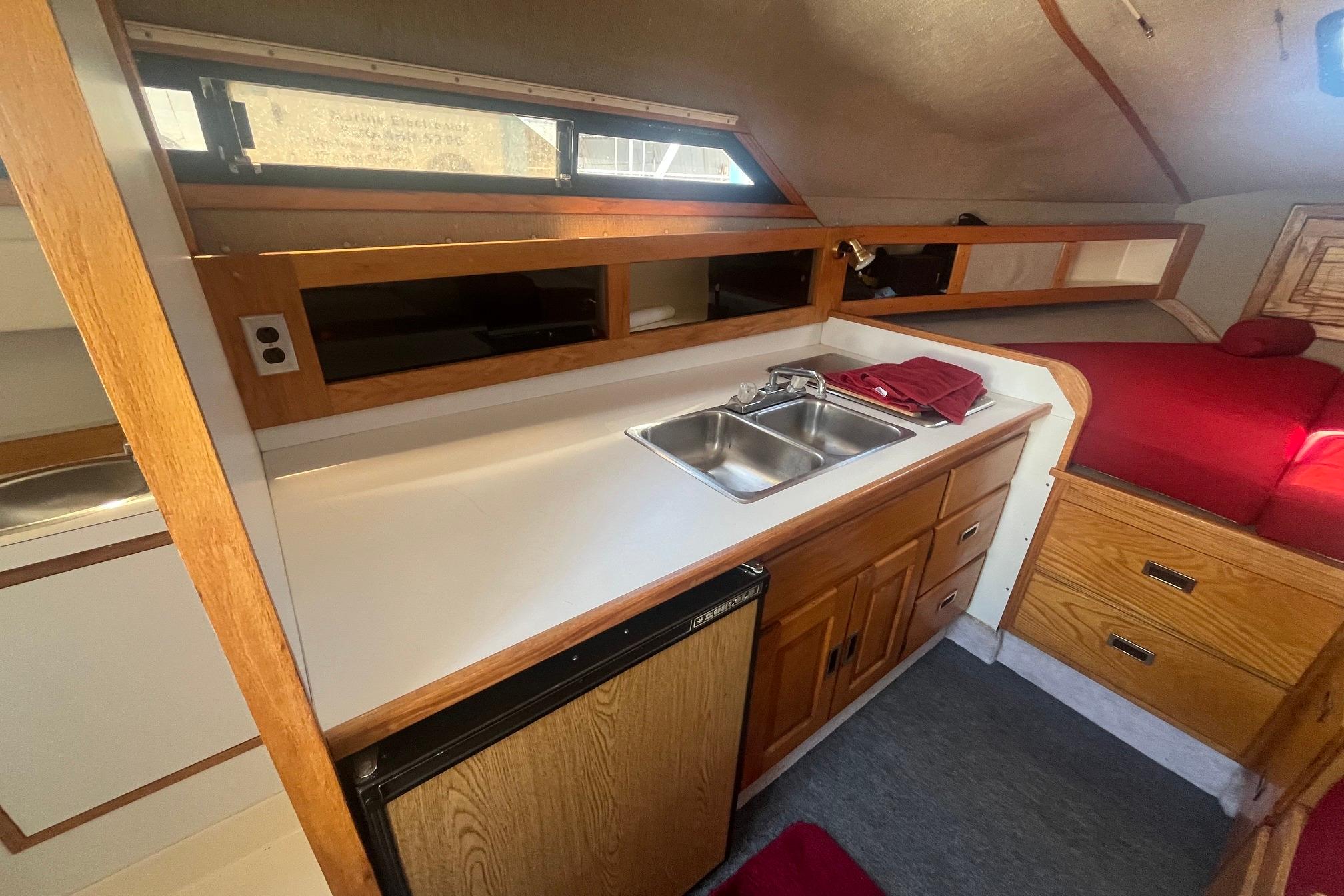 1988 Seafox 29 Flybridge interior with kitchenette, sink, and cozy sleeping area.