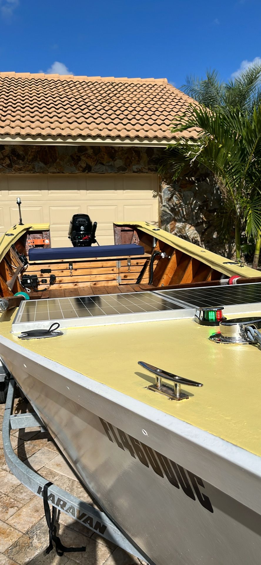A 2021 Custom Dory boat on a trailer in front of a garage.