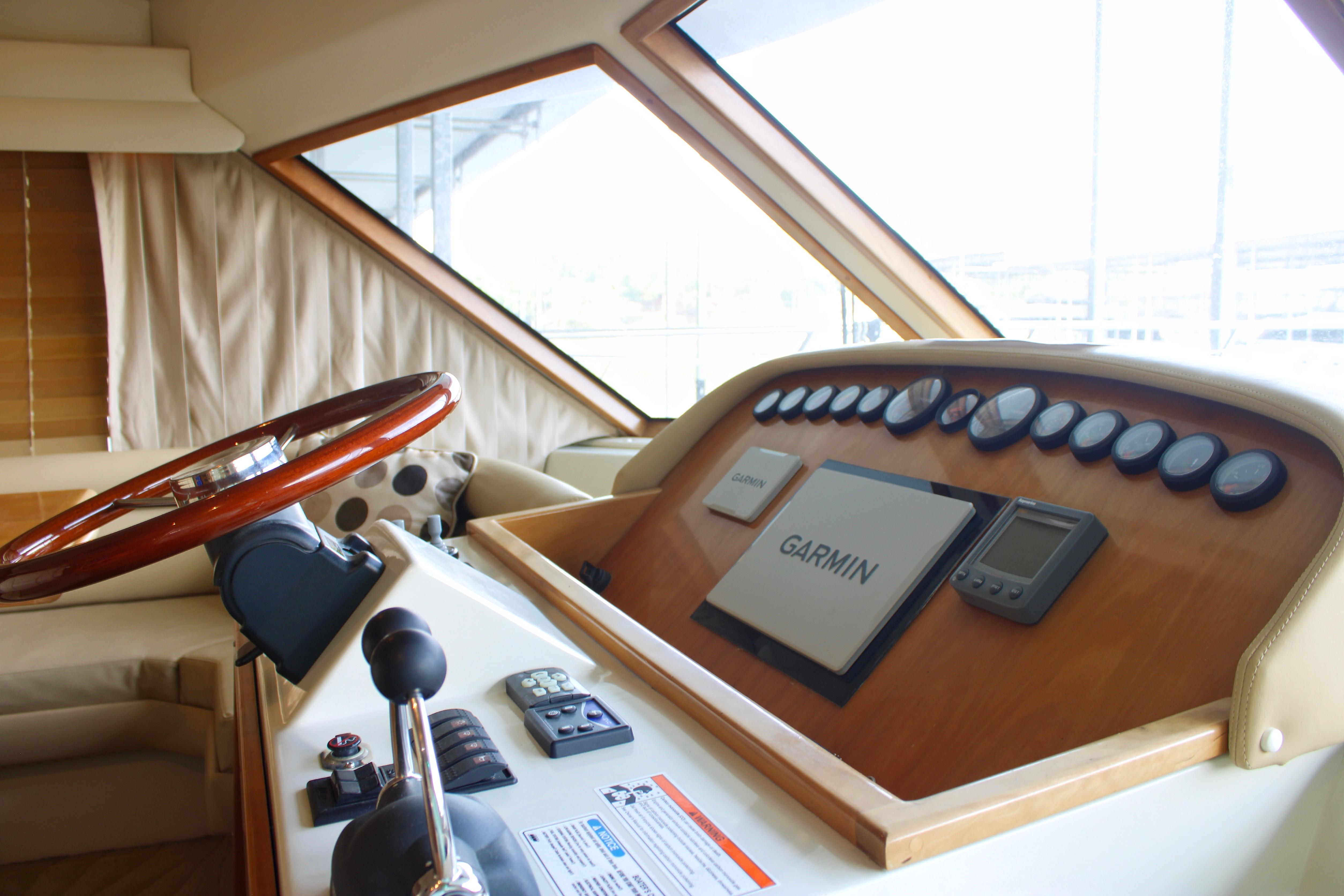 Helm of 2007 Navigator 5100 yacht with Garmin navigation system and wooden steering wheel.