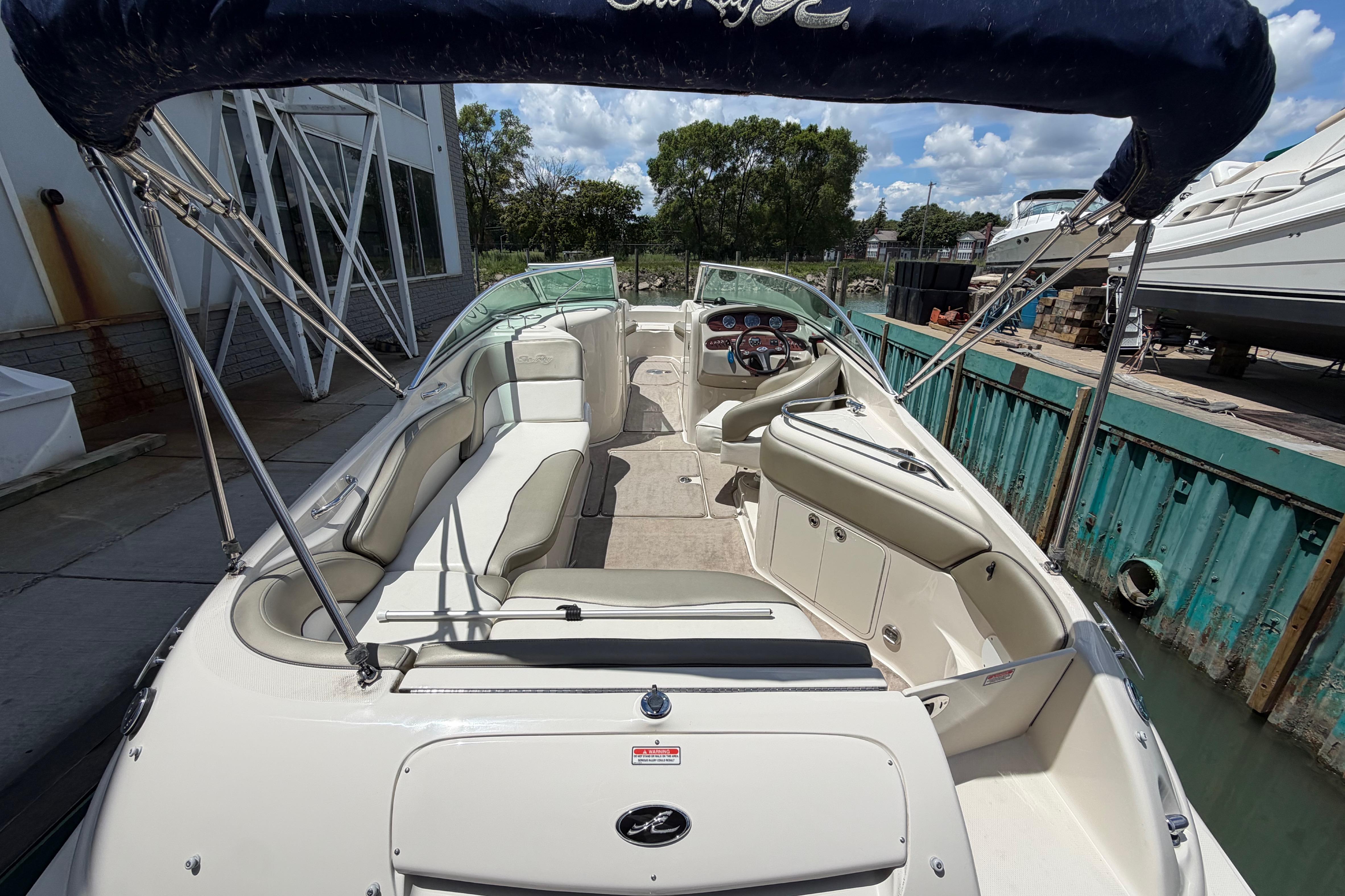 2004 Sea Ray 240 Sundeck boat with spacious seating and canopy, docked under a sunny sky.