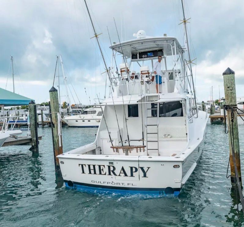 A 1979 Hatteras sport fishing boat docked in a marina. It features rod holders and a flybridge.
