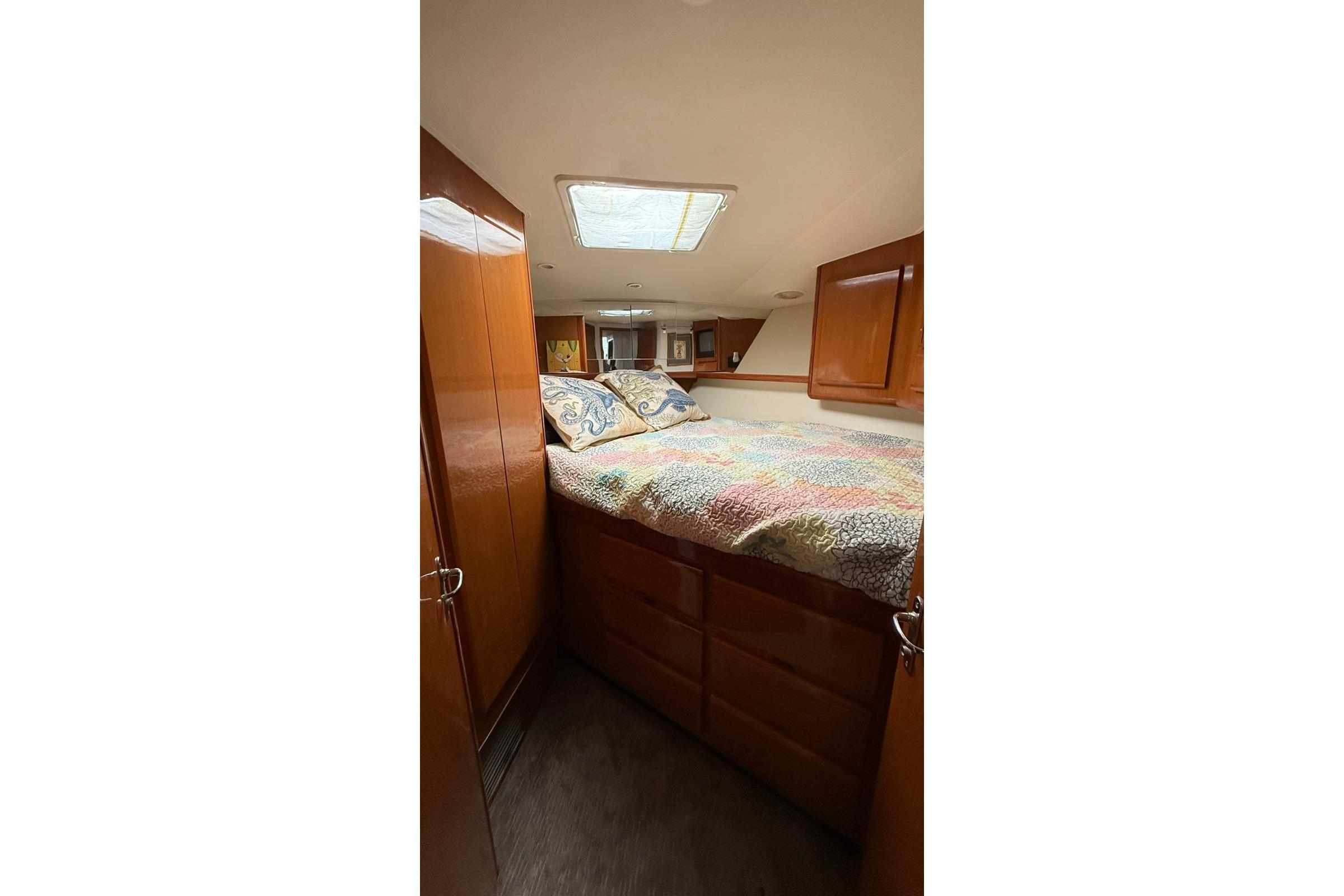1999 Viking 50 Convertible yacht bedroom with wood cabinets and colorful bedding.