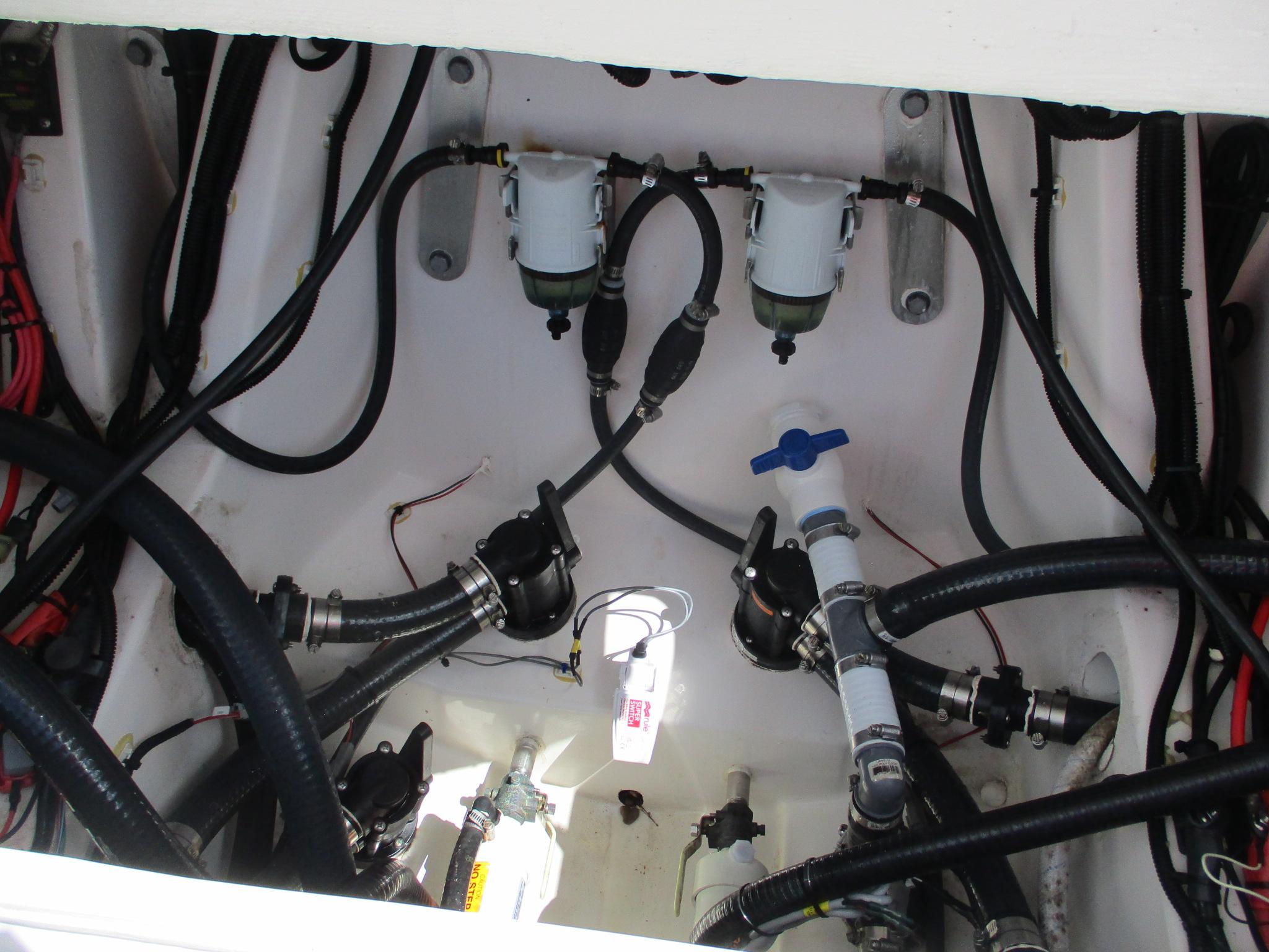 Engine compartment of 2024 Blue Wave 2800 Makaira boat, showing hoses and filters.