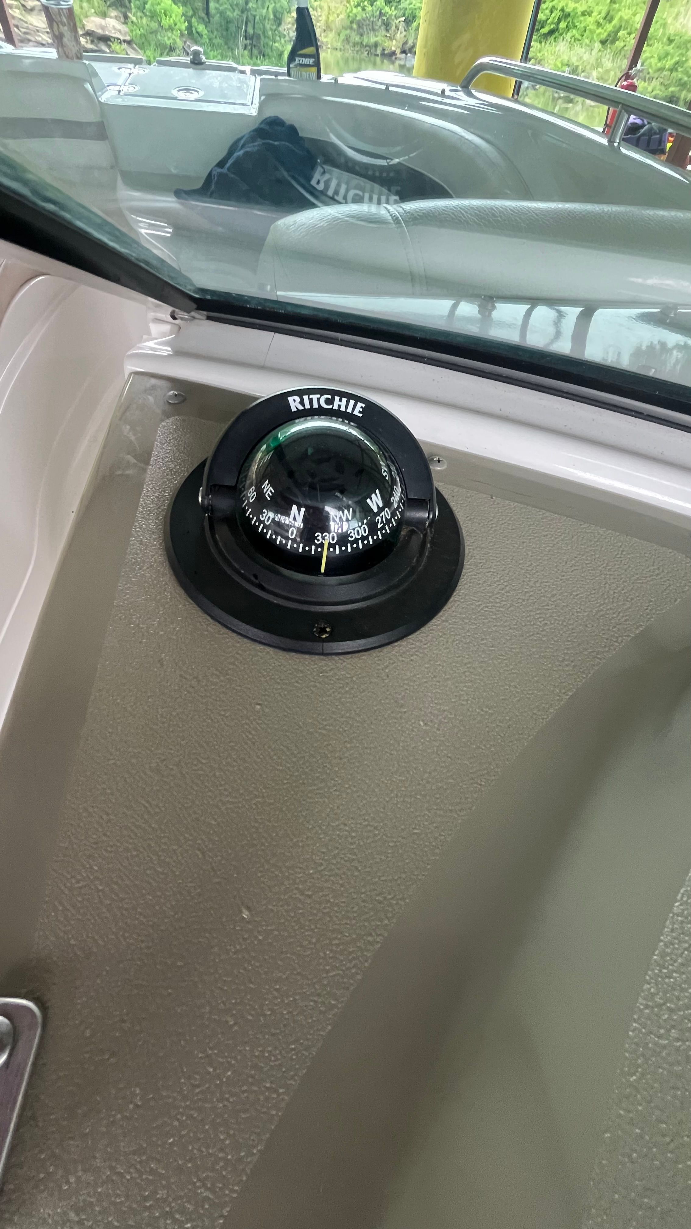 A compass is mounted on the dashboard of a boat.
