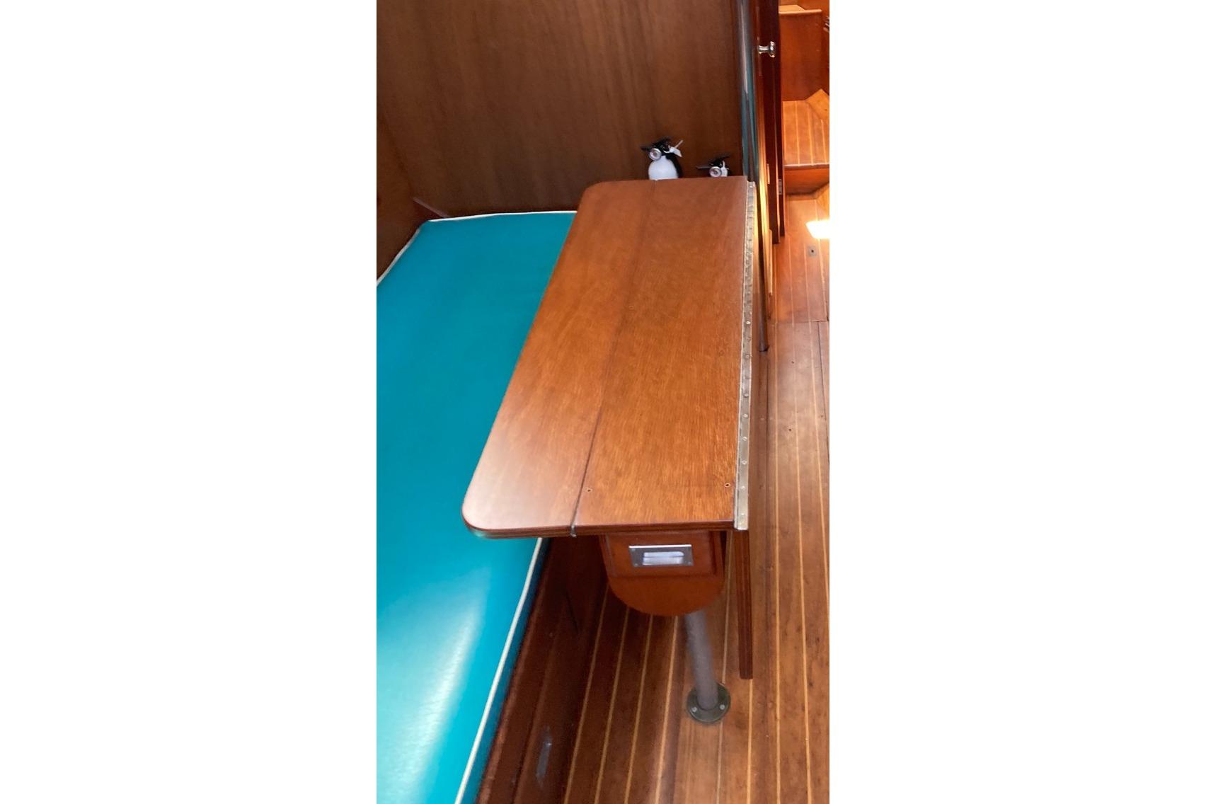 Interior of 1964 Hinckley Pilot 35 sailboat with wooden table and turquoise seating.