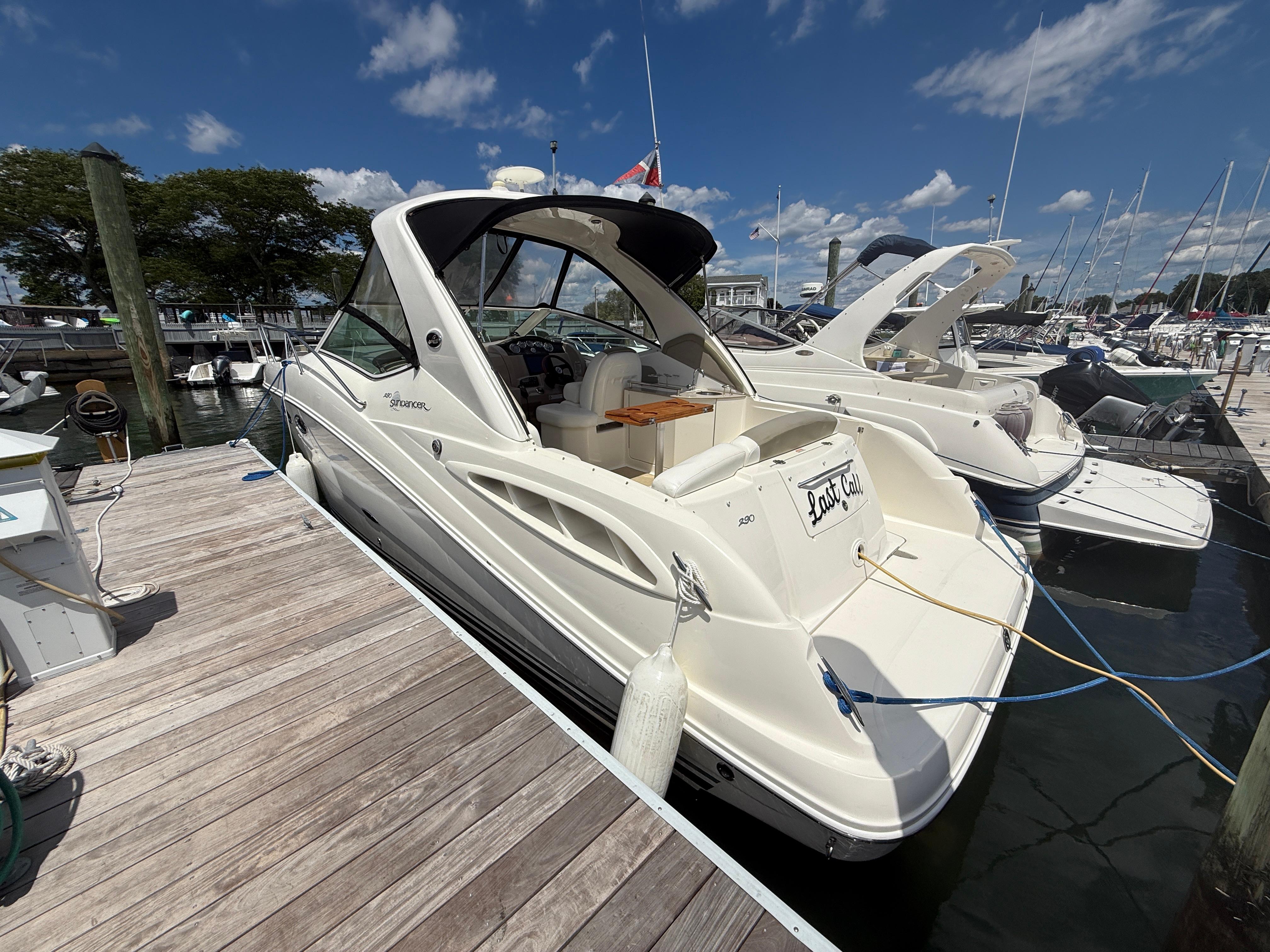 2006 Sea Ray 290 Sundancer docked at marina under blue sky.