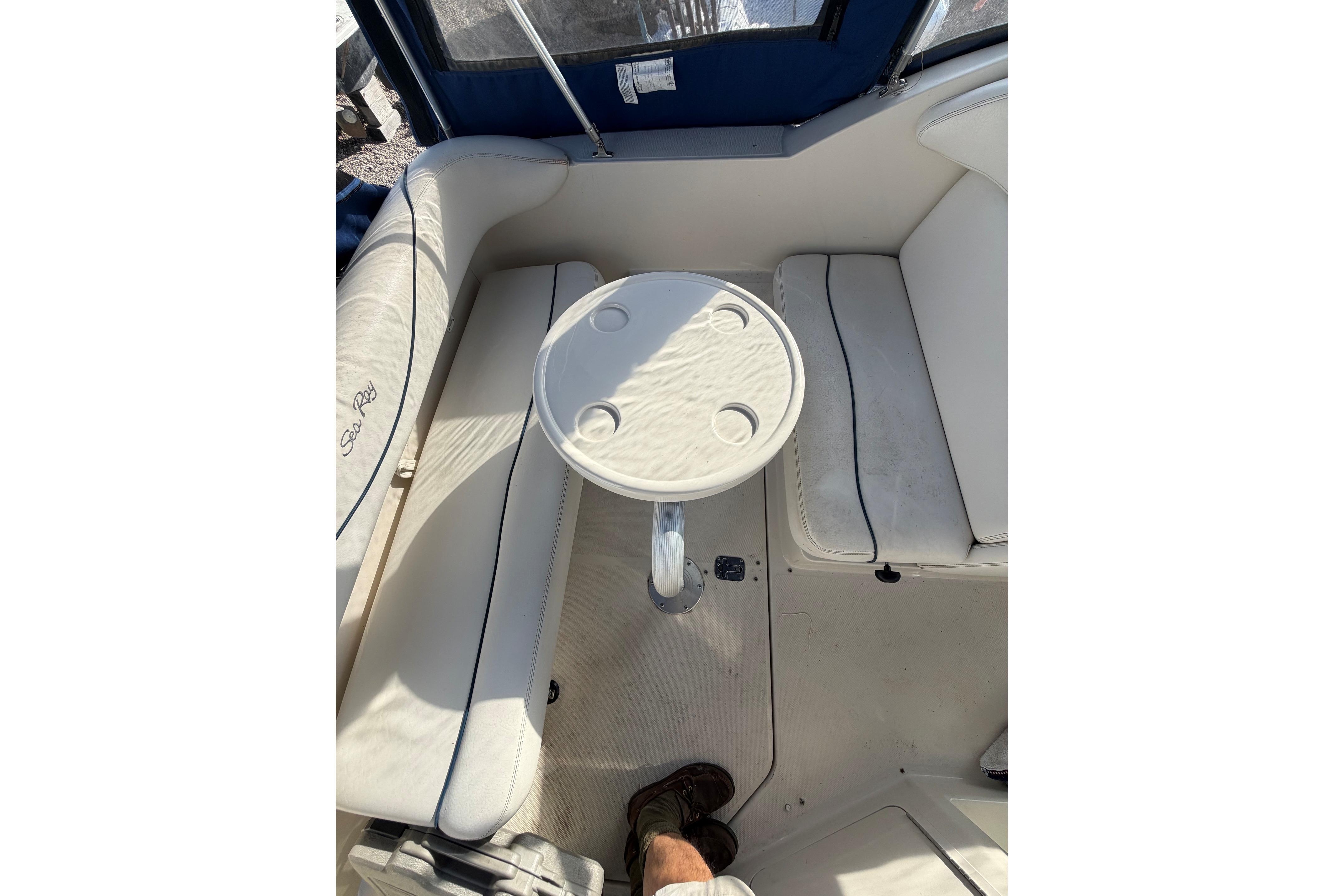 Interior seating area of a 2000 Sea Ray 240 Sundancer boat with table.