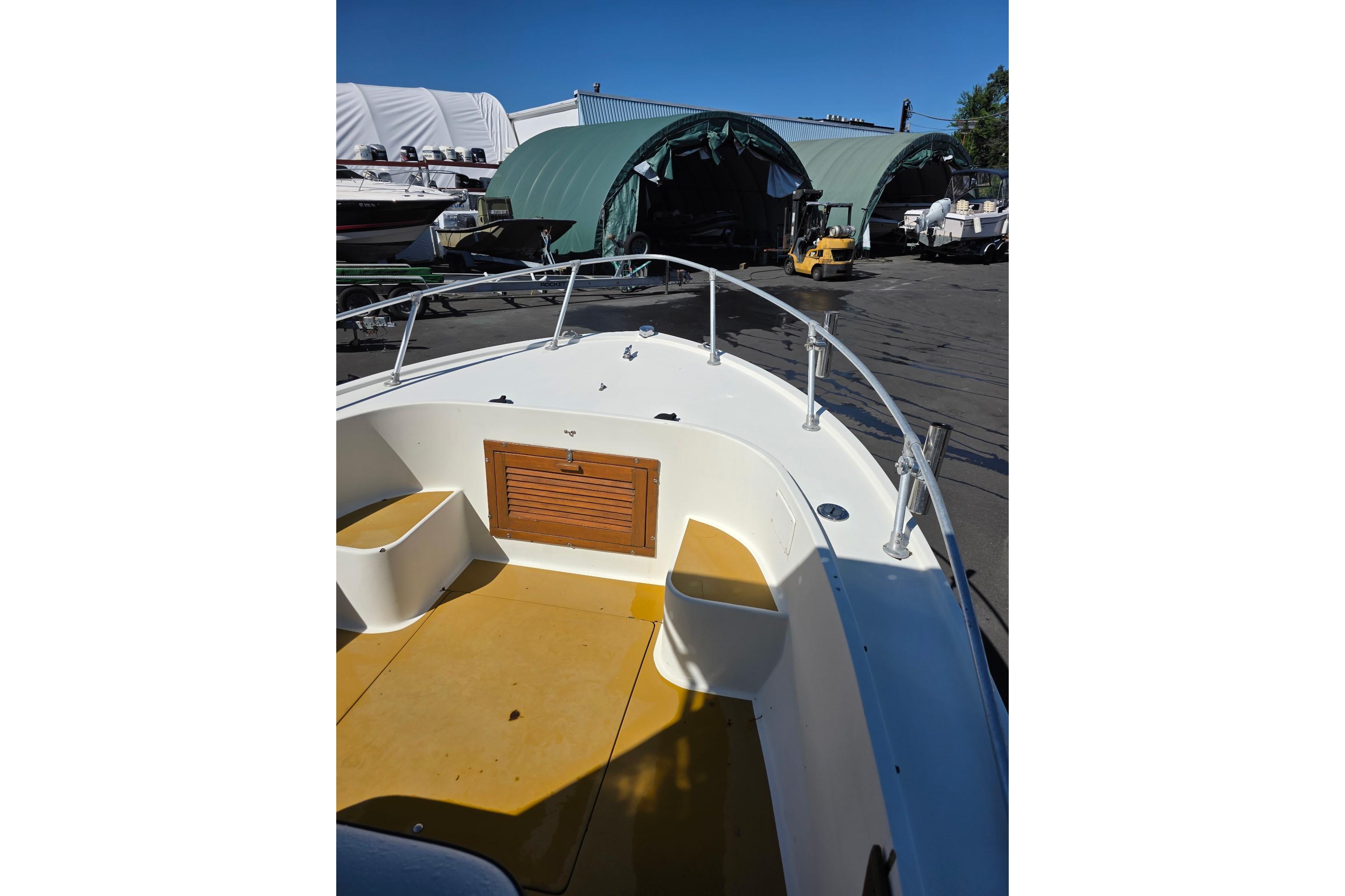1982 Mako 20 Center Console boat docked near storage sheds under clear blue sky.