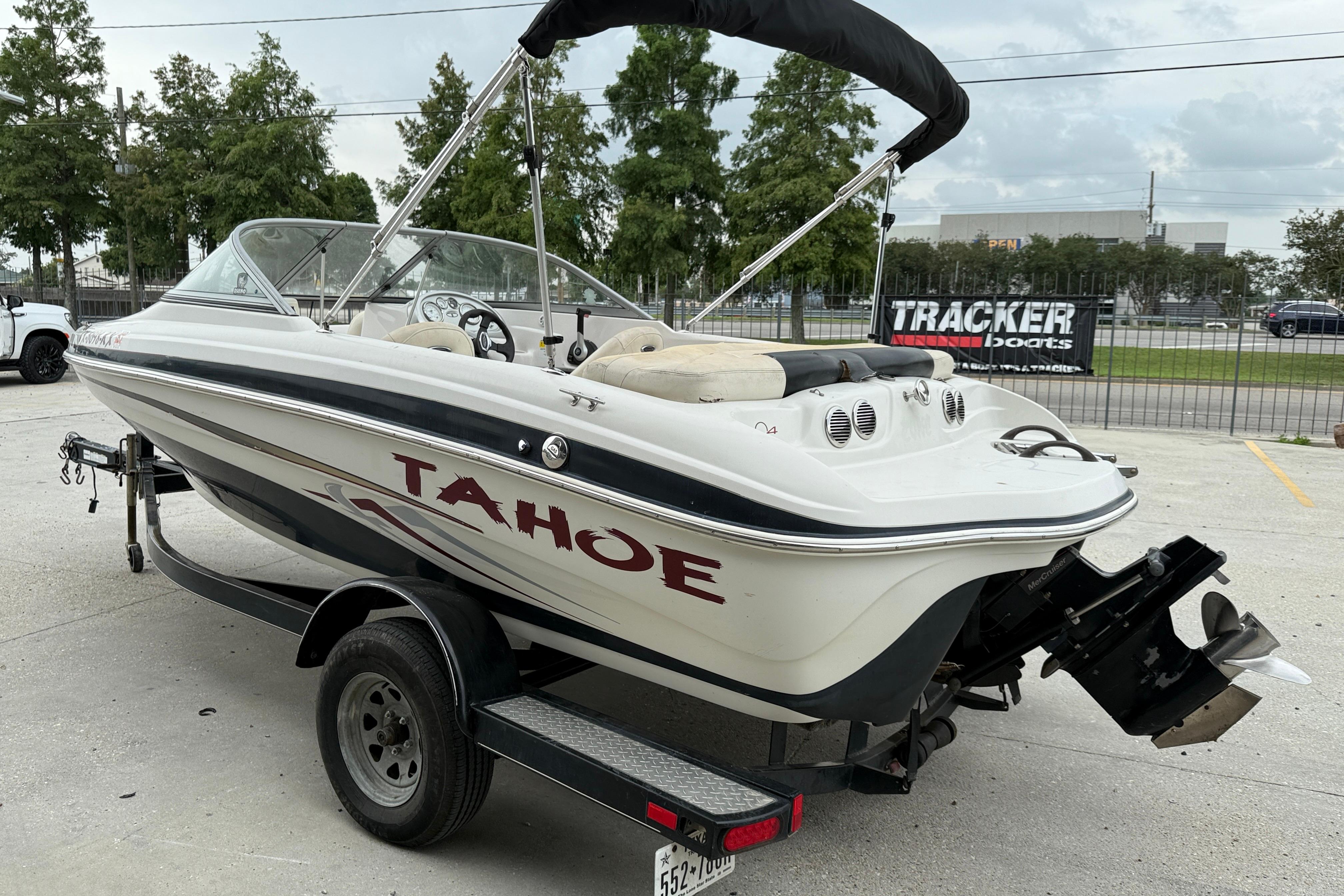 2010 Tahoe Q4 boat on trailer, parked outdoors, with canopy and visible engine.