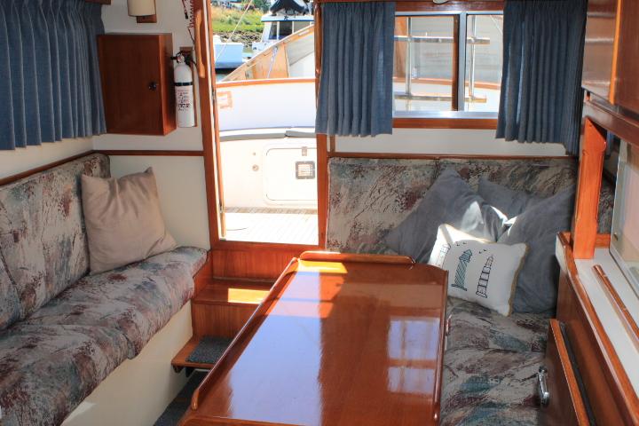 Cozy interior of a 1989 Eagle Pilothouse boat with cushioned seating and wooden table.