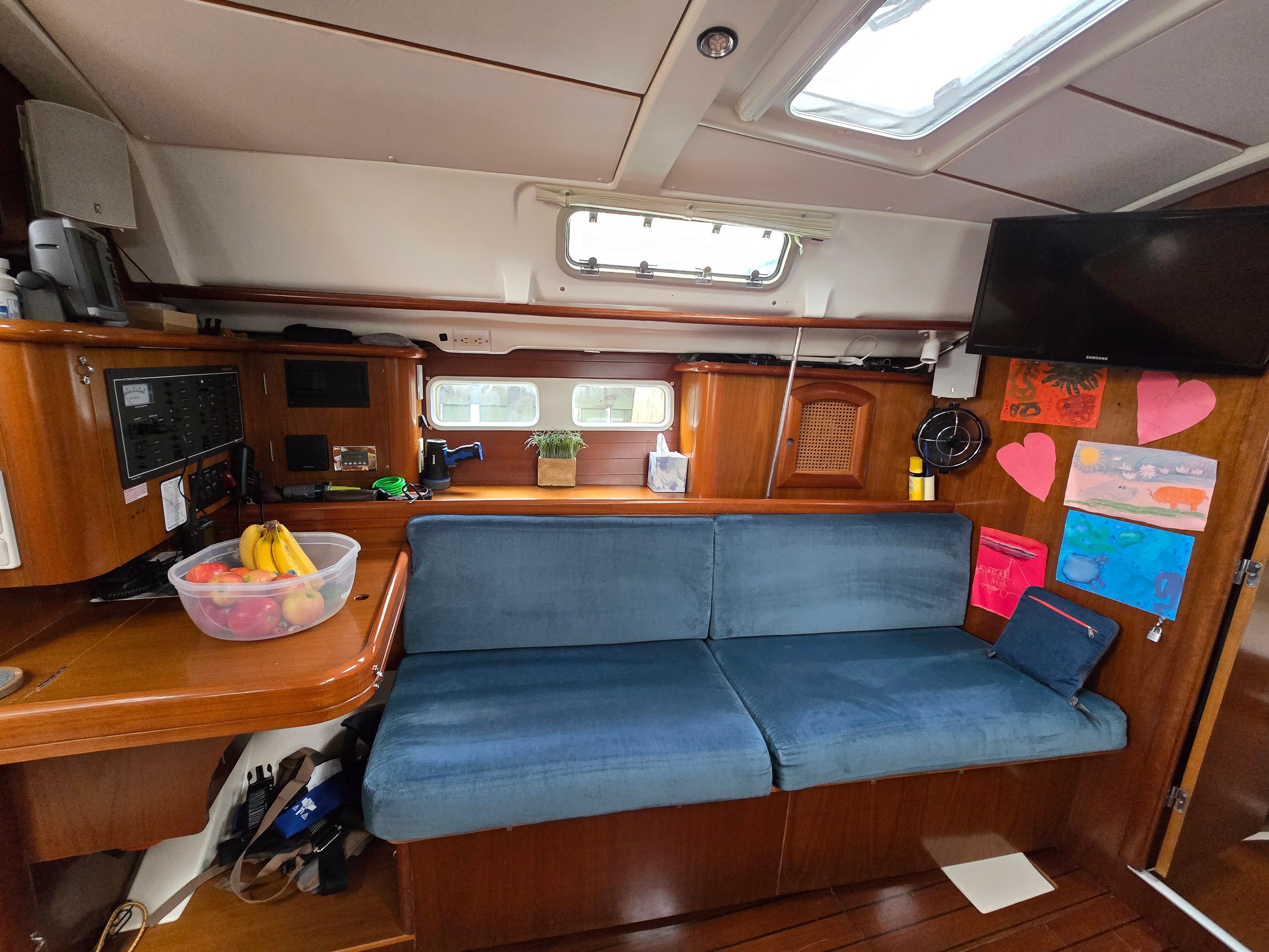 Interior of a 1998 Beneteau 411 with blue couch and wooden furnishings.