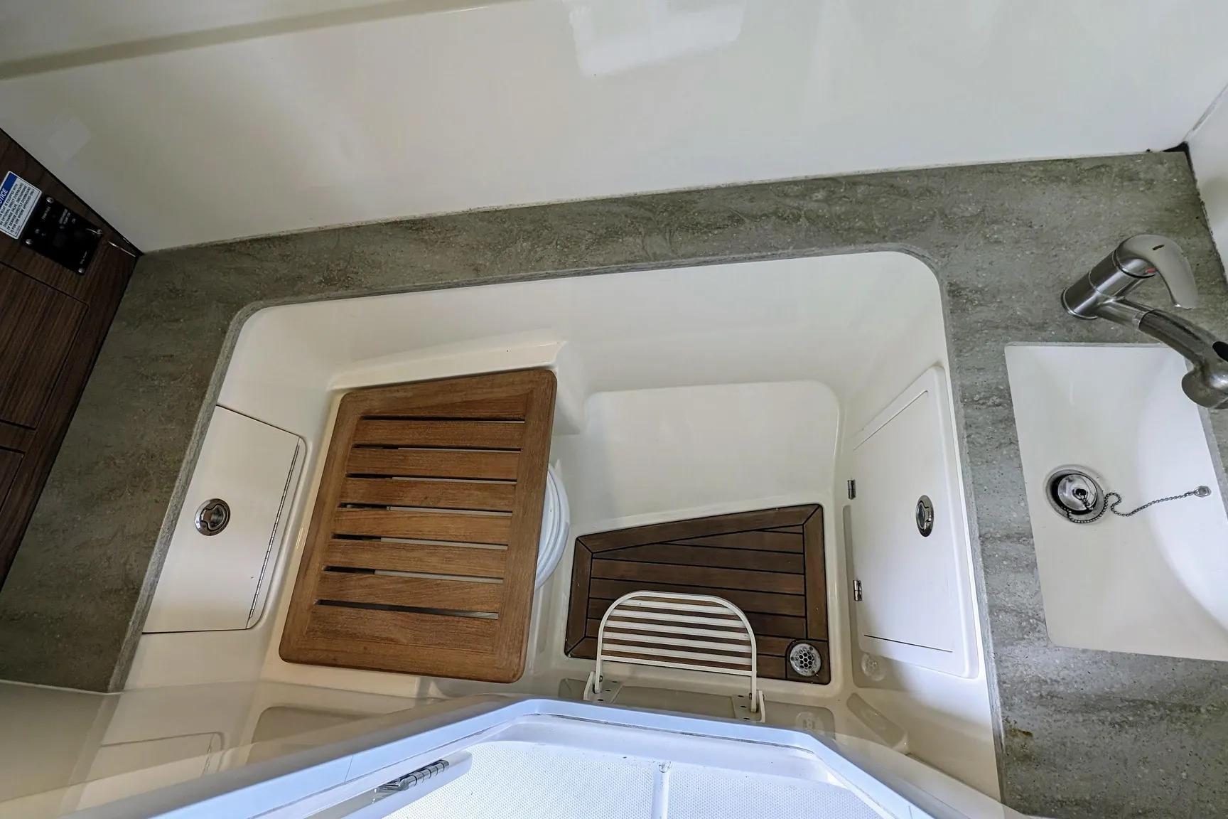 Interior of 2017 Boston Whaler 320 Vantage boat, featuring a compact sink and wooden flooring.