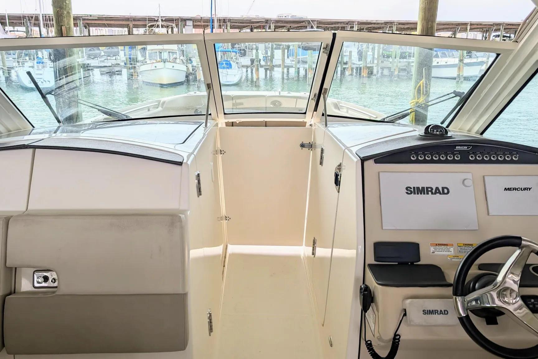 2017 Boston Whaler 320 Vantage helm with Simrad navigation, docked at marina.