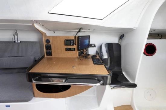 Navigation station inside 2024 Jeanneau Sun Fast 3300 yacht with control panel and seating.