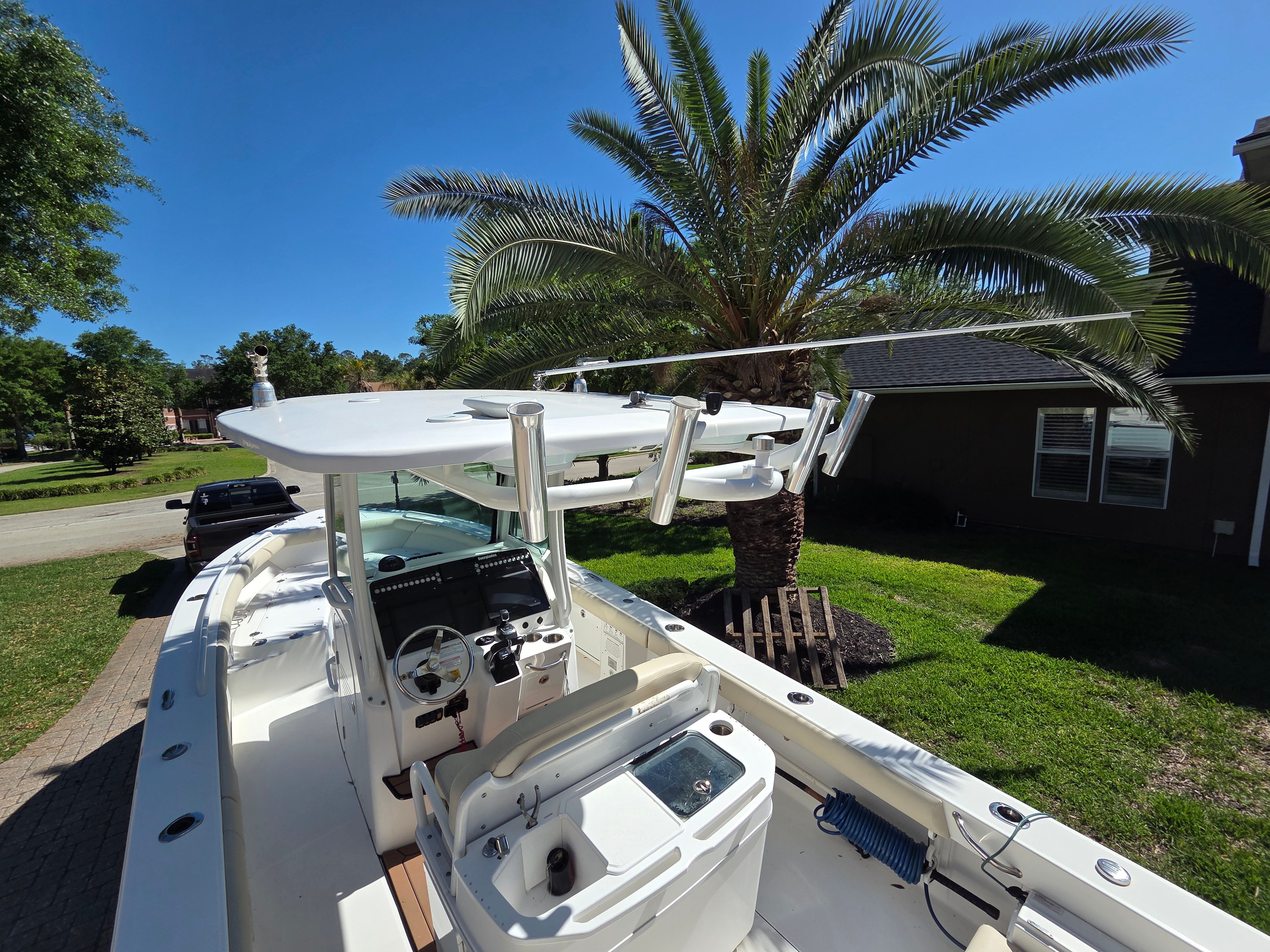 A 2017 Everglades 273 Center Console boat is on a green lawn under palm trees.