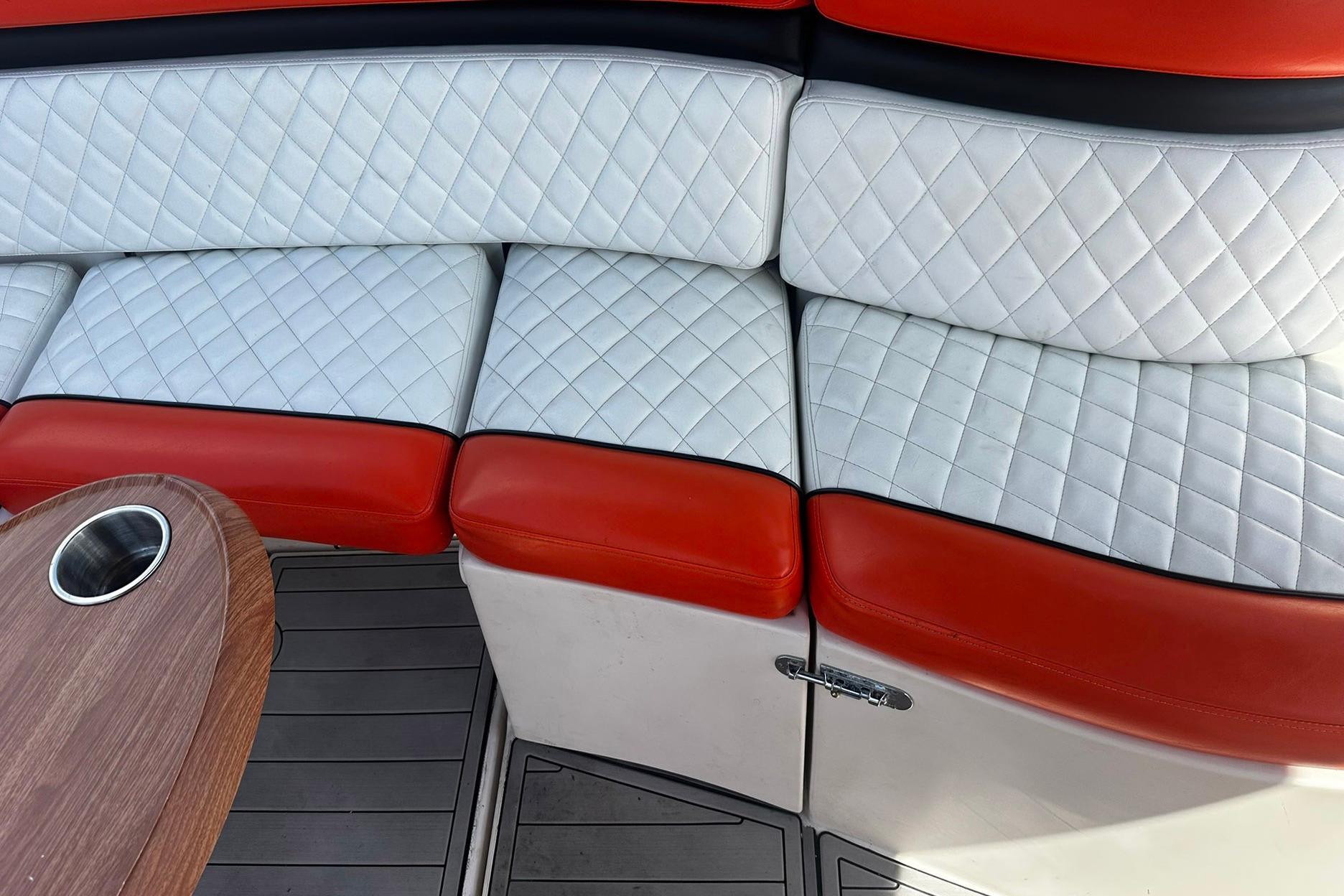 Luxurious seating on 2012 Rinker 310 Express Cruiser LE with quilted upholstery and wooden table.
