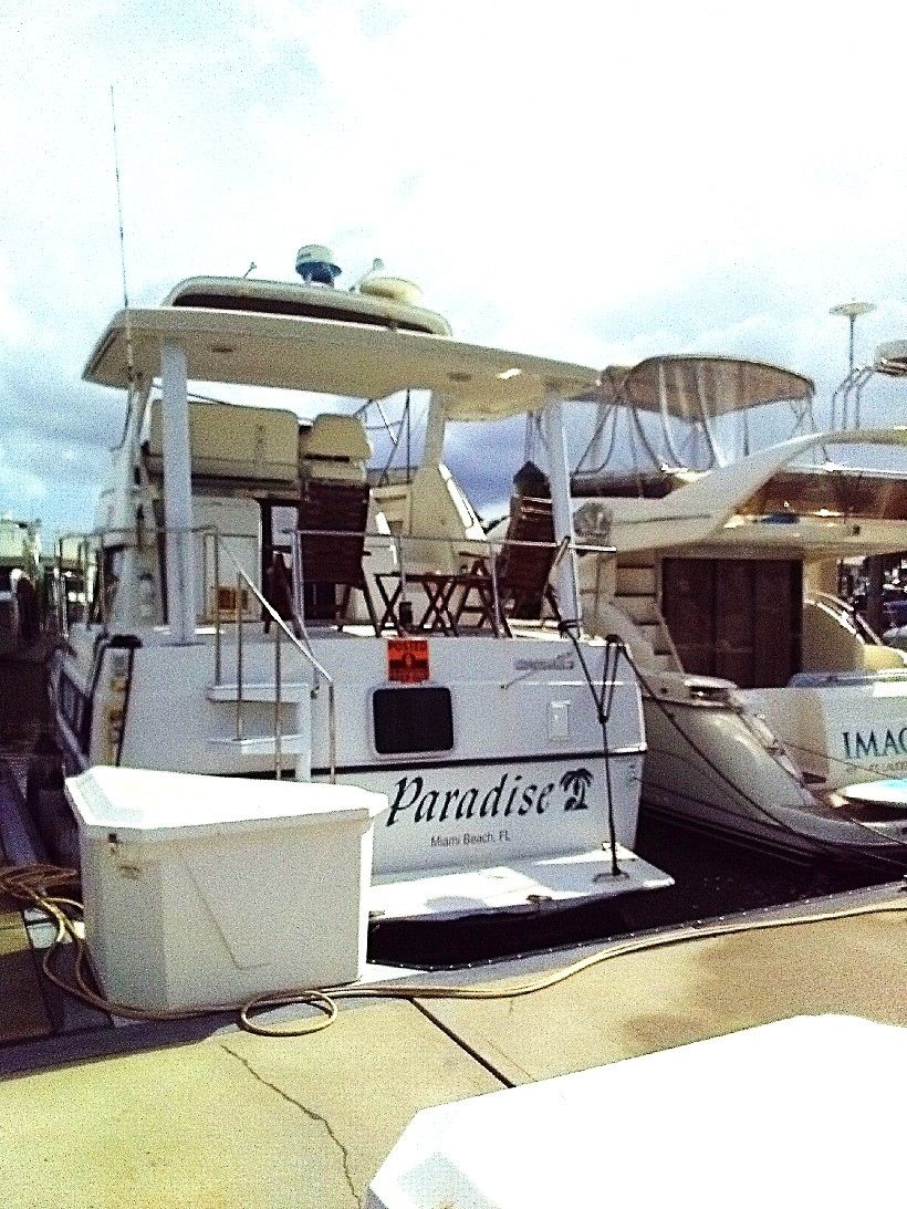 1995 Carver 35 at dock, featuring a covered upper deck and seating area.