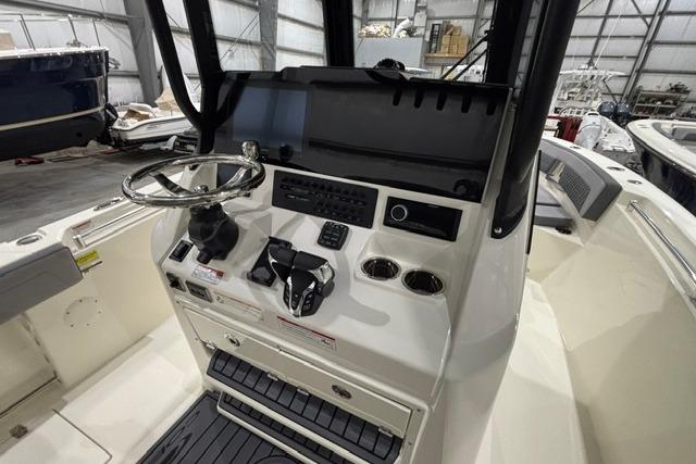2026 Cobia 245 Center Console boat dashboard with steering wheel and controls in a storage facility.