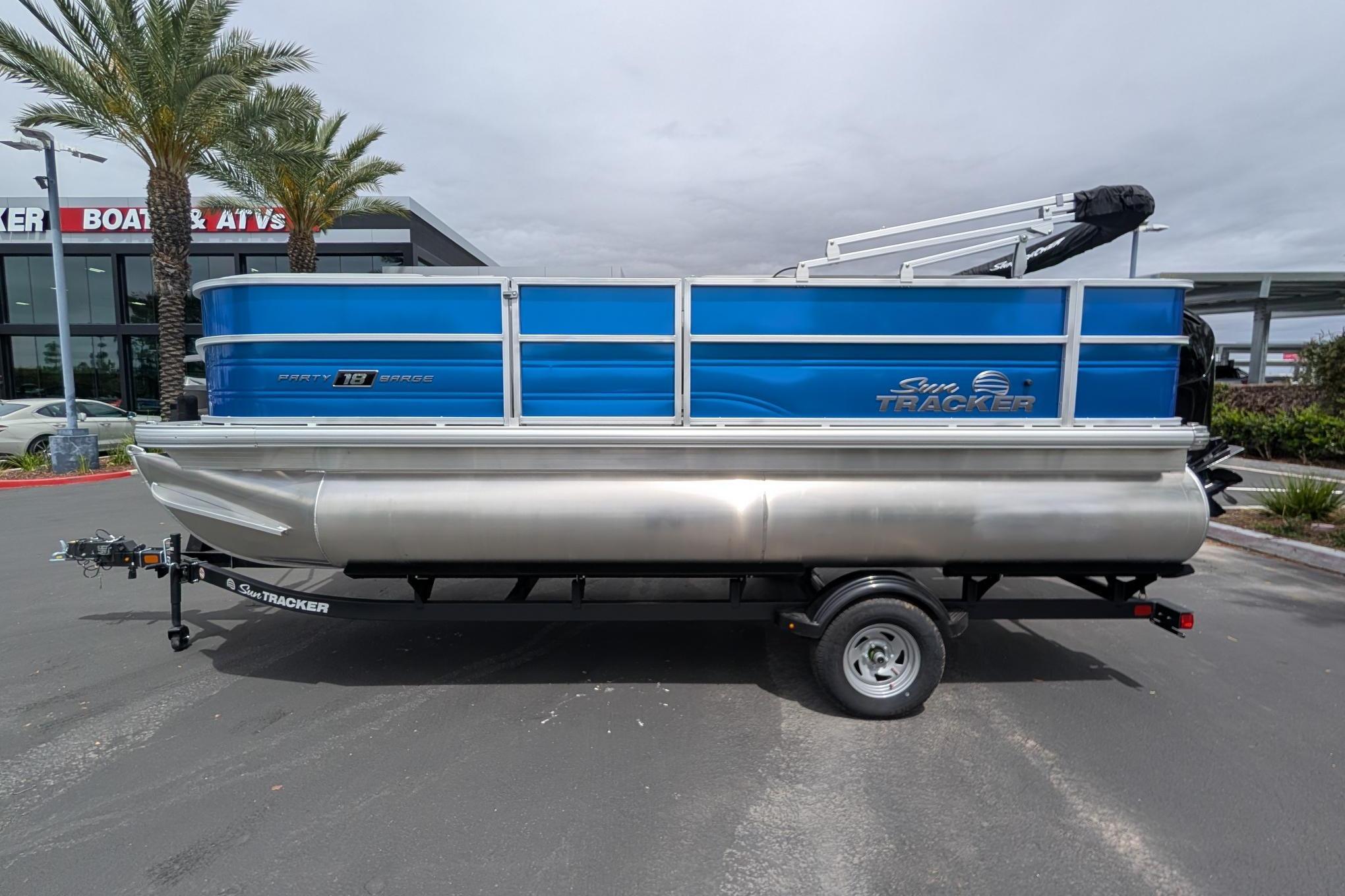 2026 Sun Tracker Party Barge 18 DLX pontoon boat on trailer, parked outdoors.