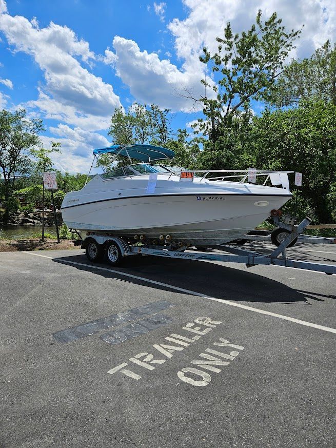 A 1998 Crownline 210 CCR boat on a trailer in a parking lot.