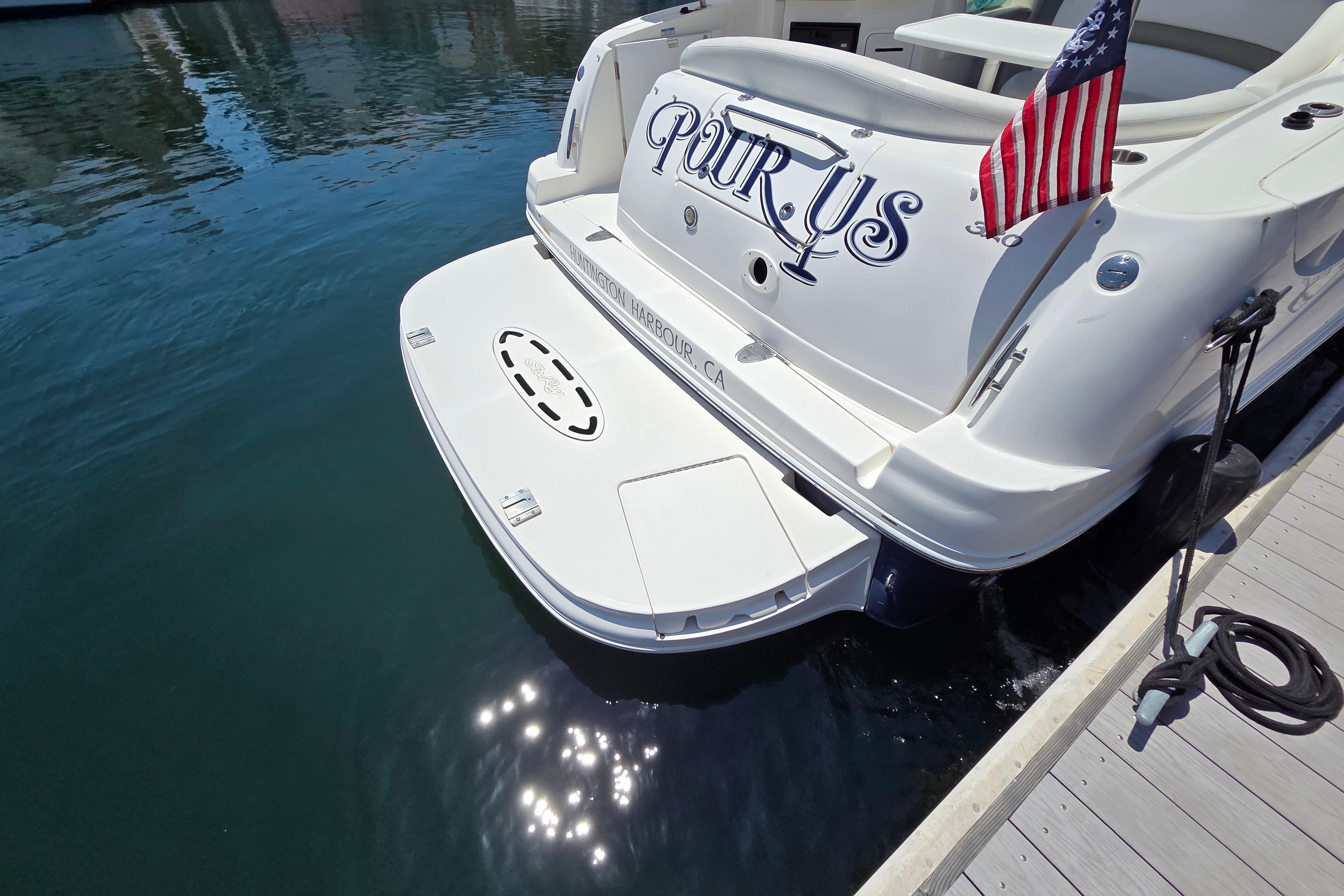 2006 Sea Ray Sundancer 320 docked, displaying American flag and custom name, in sunny marina.