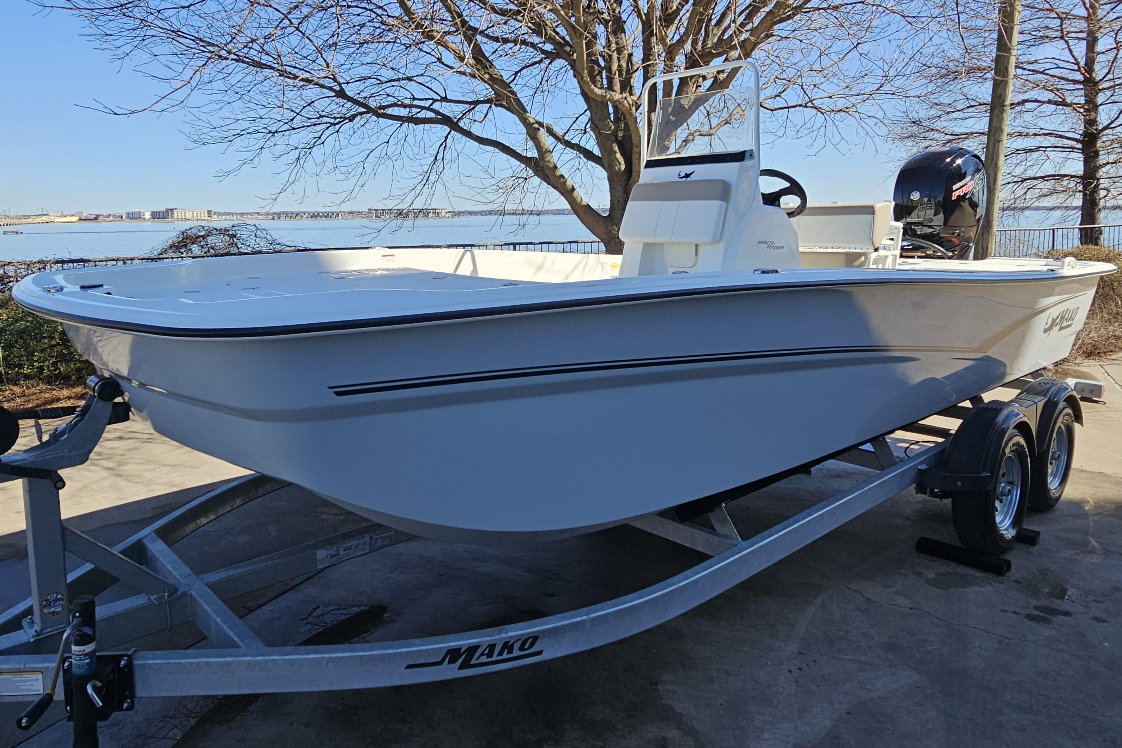 2026 Mako Pro Skiff 19 CC boat on trailer by waterfront, under clear blue sky.