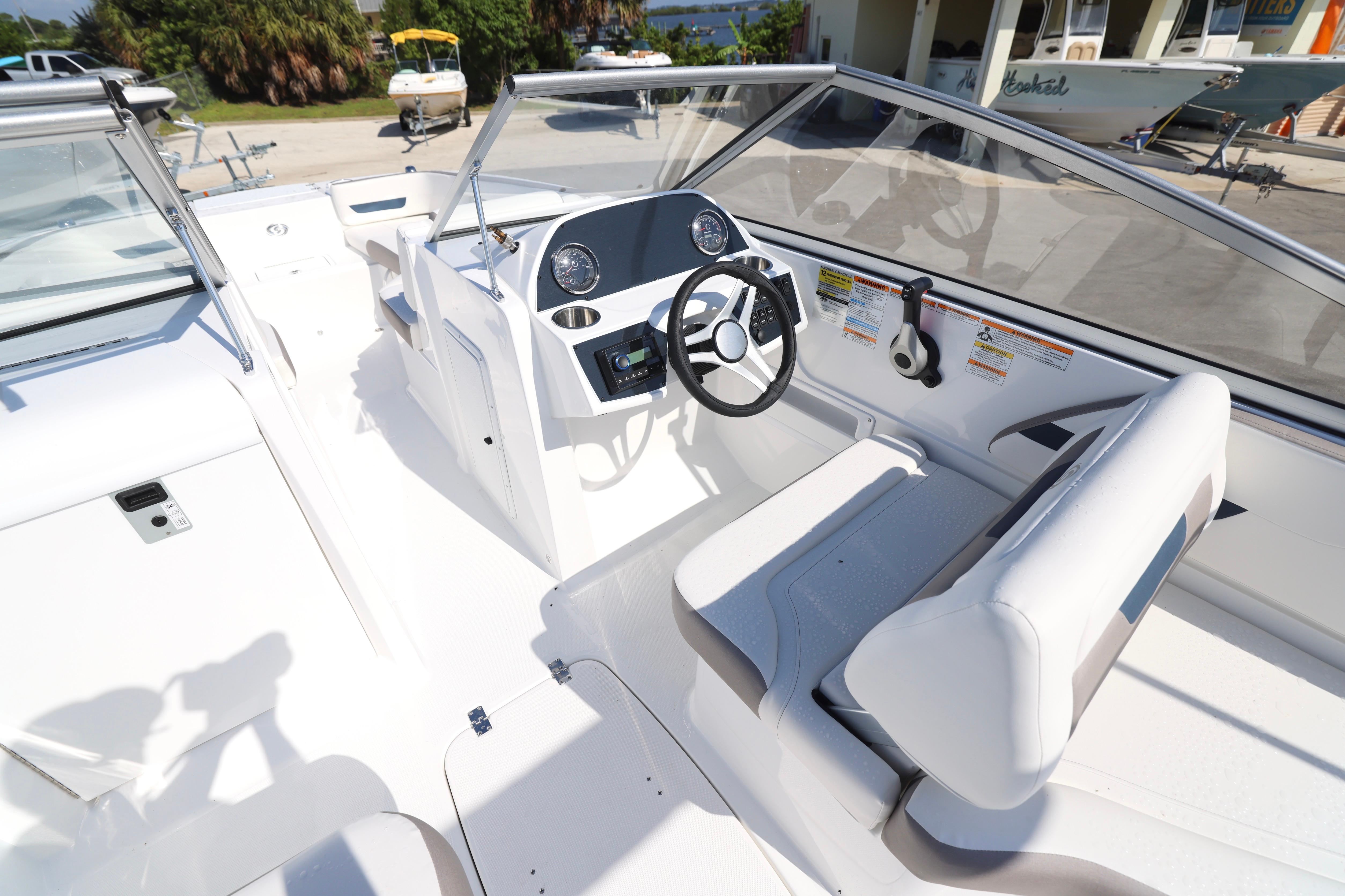 2026 Hurricane SunDeck 235 OB boat interior with steering wheel and seating.