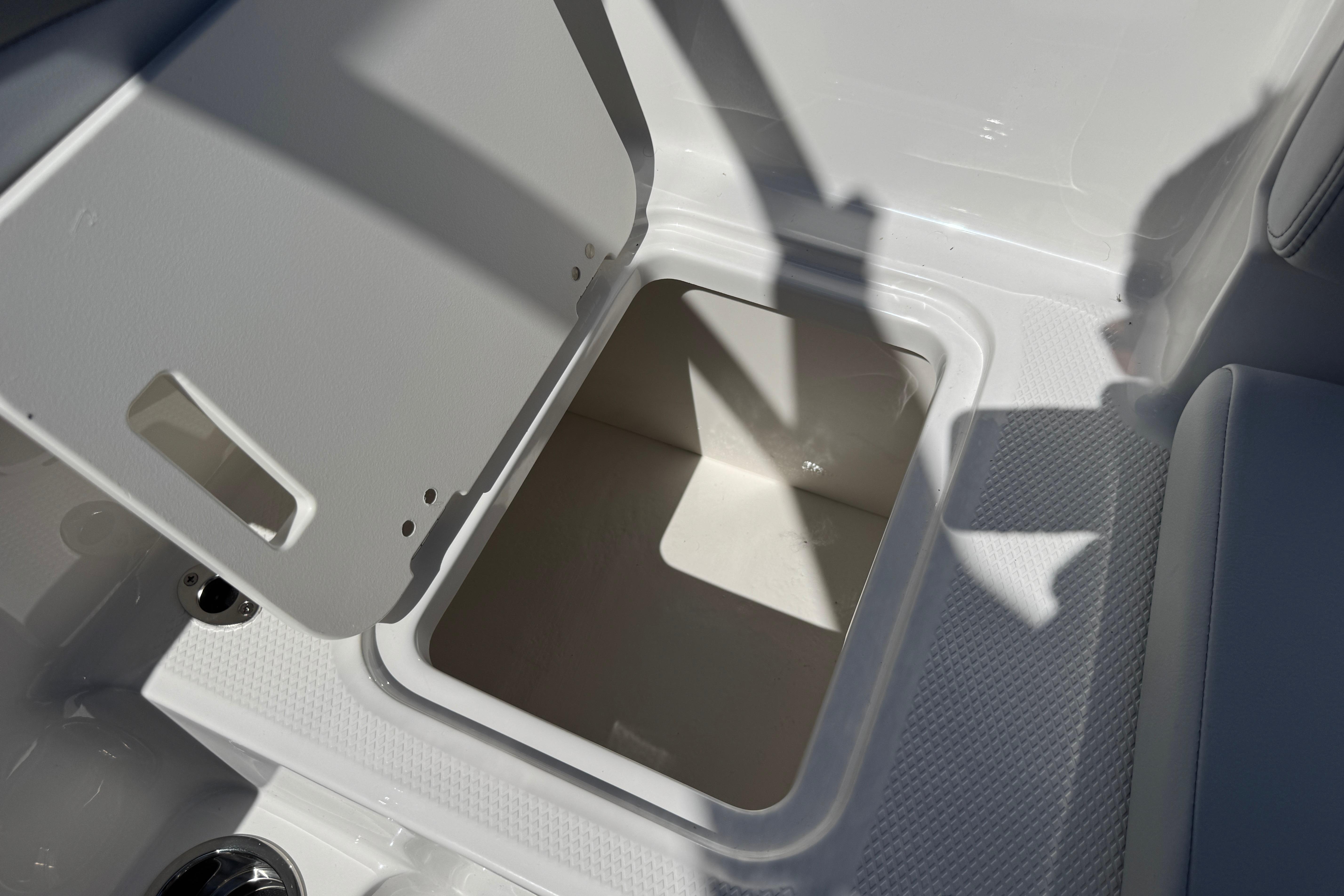 Open storage compartment on 2026 Chaparral 21 SSi boat, showcasing interior space.
