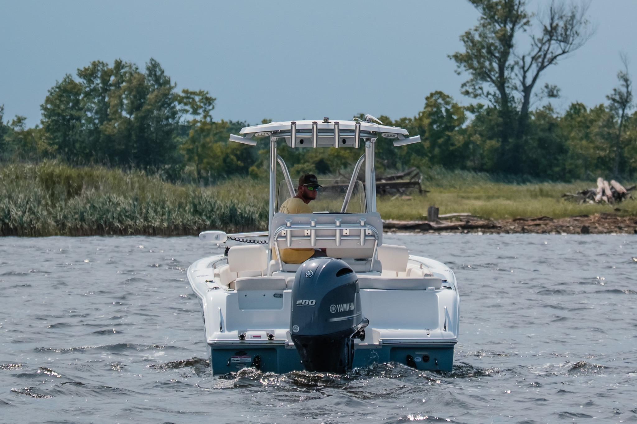 2022 Sea Hunt Ultra 229 boat cruising on a lake with trees in the background.