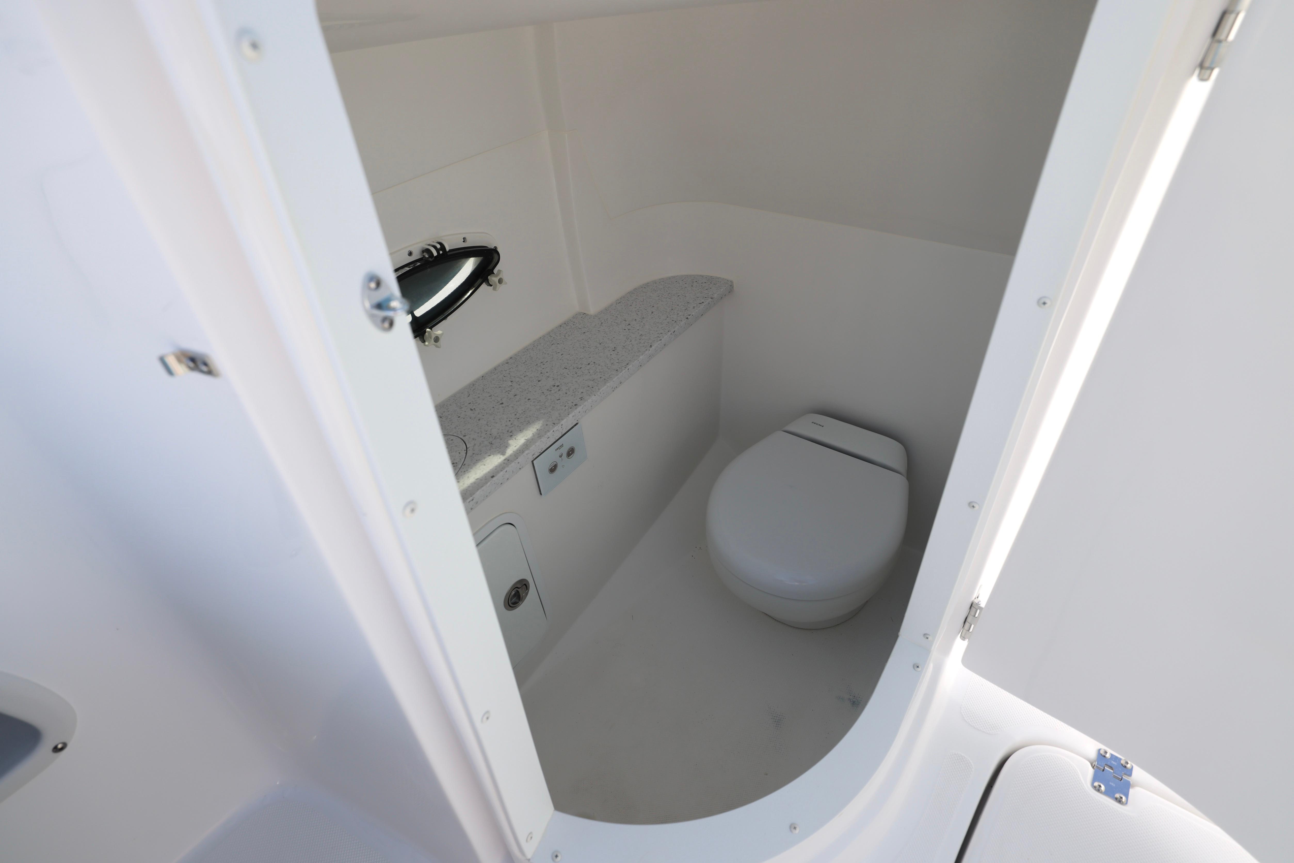 Interior of 2026 Hurricane SunDeck 2486 OB boat bathroom with toilet and porthole.