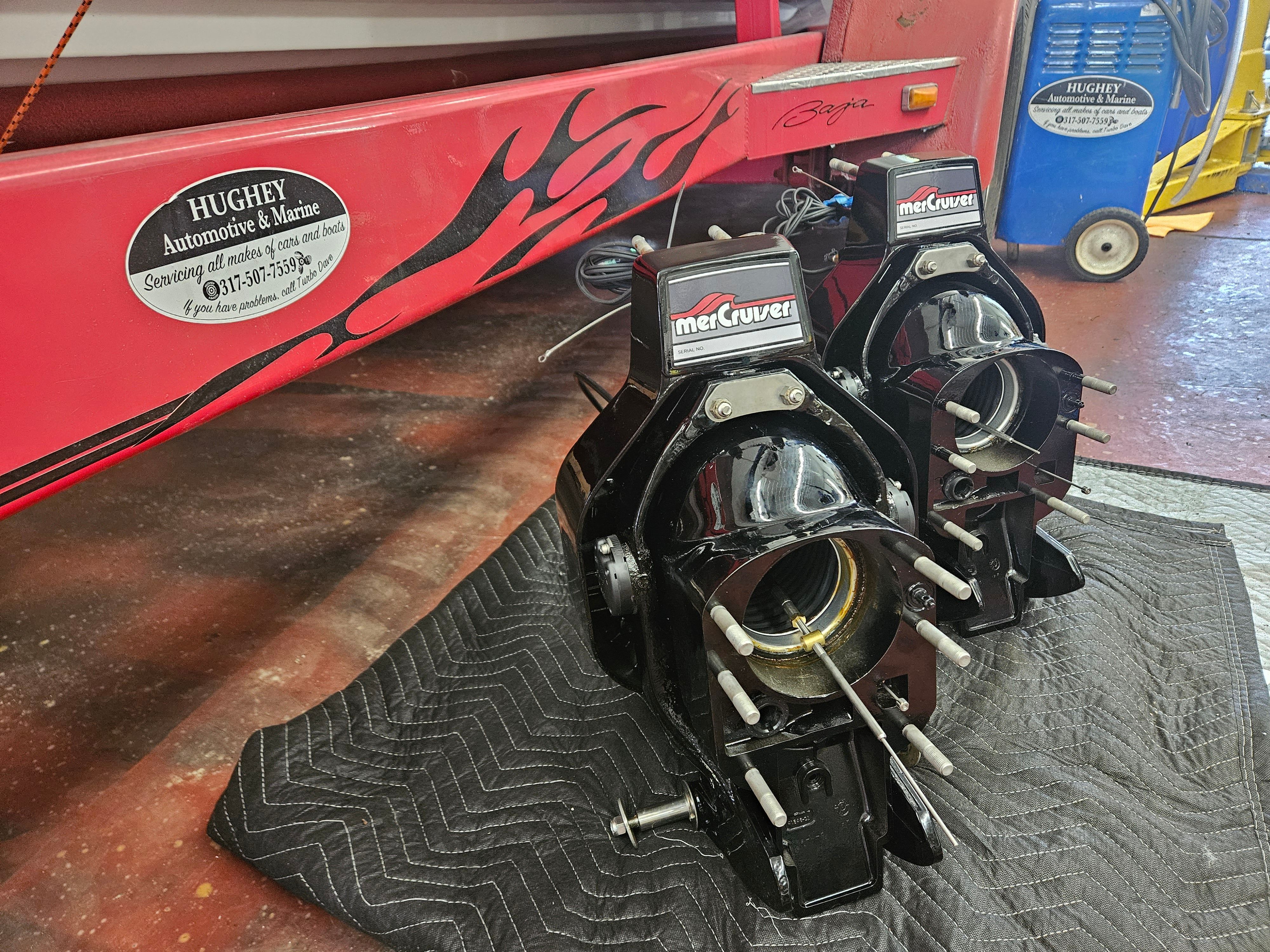 Two MerCruiser engines rest on a padded surface next to a red boat trailer.