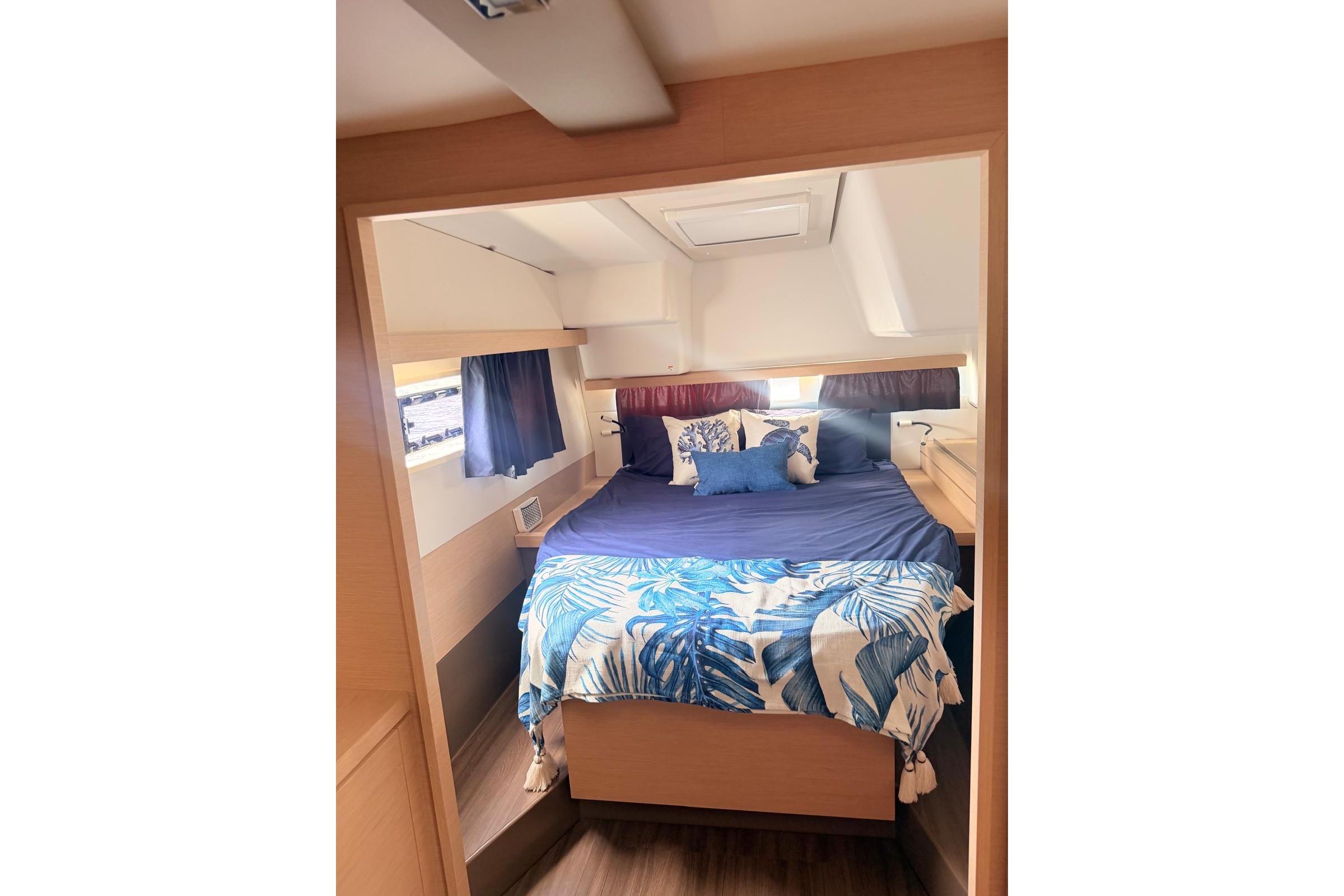 Cozy cabin interior of 2018 Fountaine Pajot Lucia 40 with nautical-themed bedding.