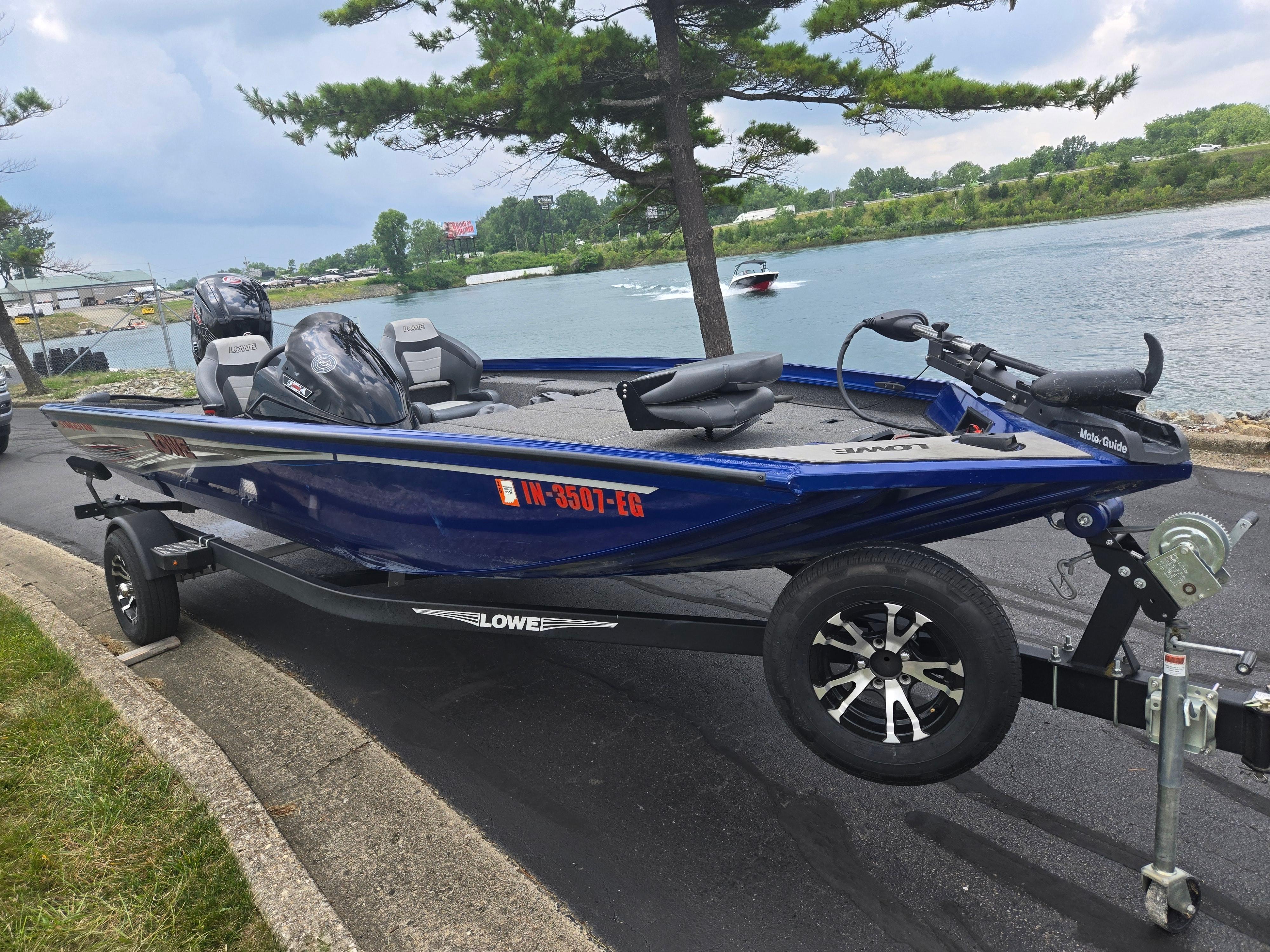 2021 Lowe Stinger 188 boat on trailer by a lake, under a cloudy sky.