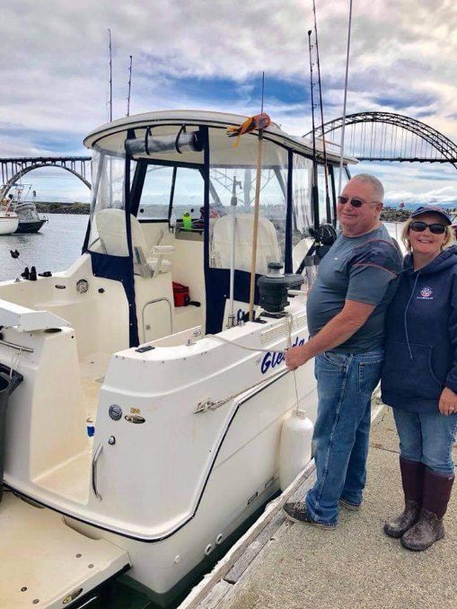 A couple stands beside a Bayliner 242 Ceara boat at the dock.