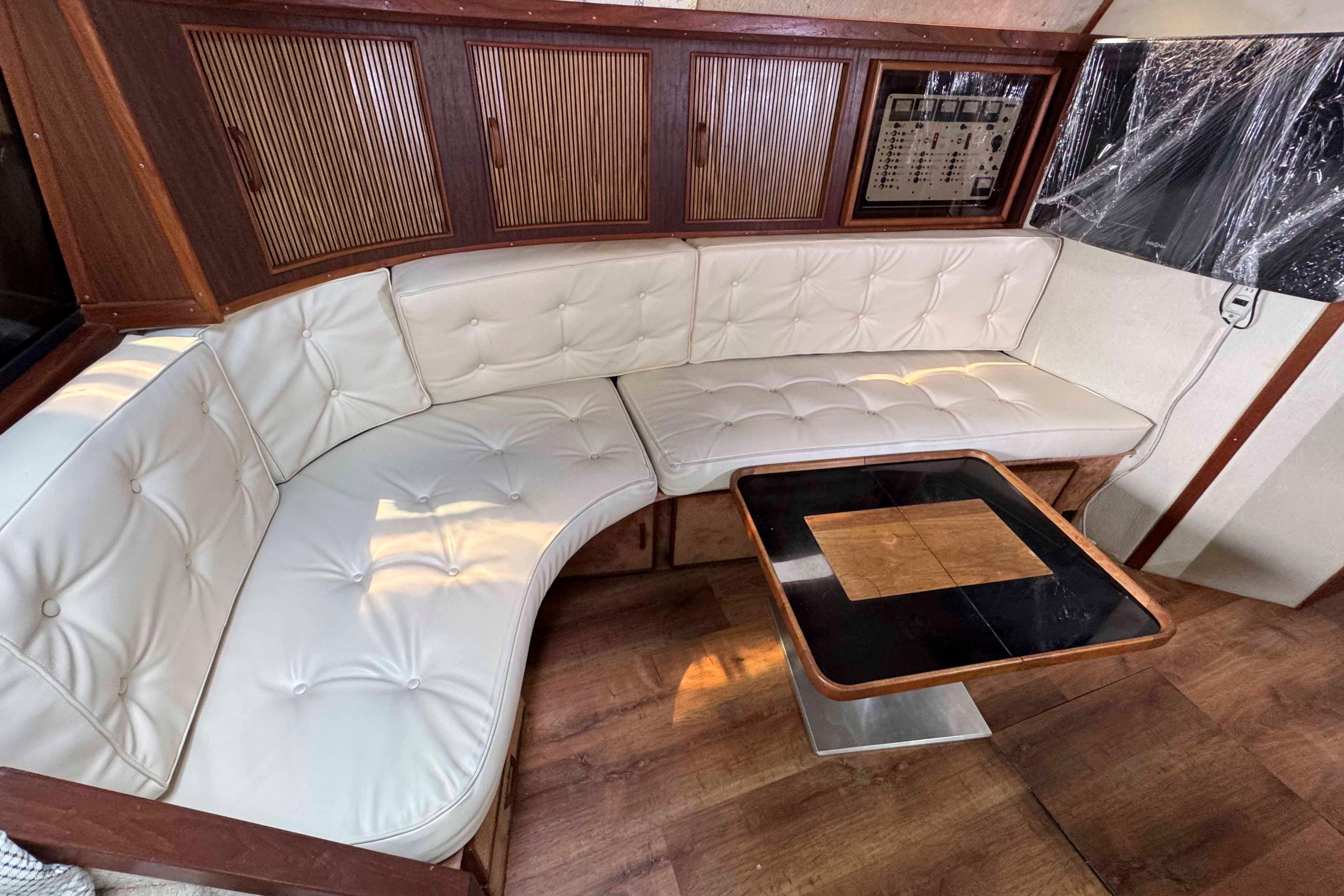1986 Sea Ray 390 Express Cruiser interior with white leather seating and wooden table.