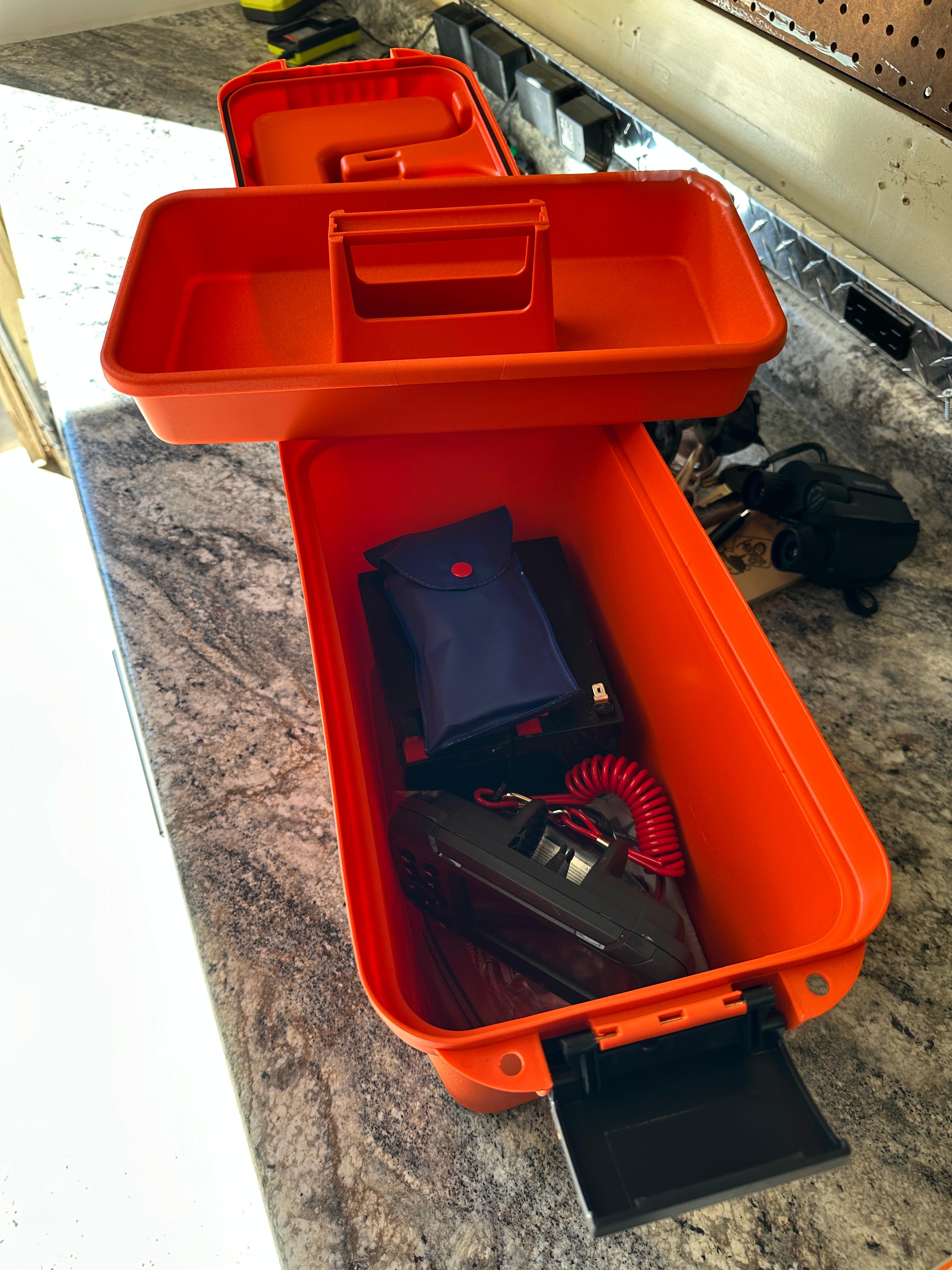 Orange Lund H toolbox from 1960 on a workbench, containing various tools.