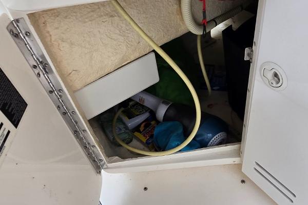 Storage compartment in a 1999 Sea Ray 280 SS boat with various items inside.