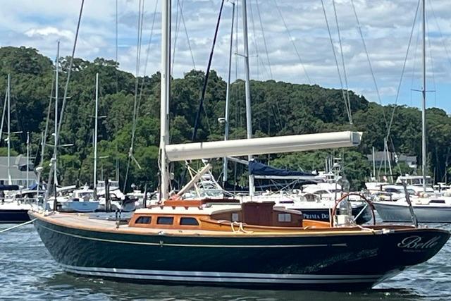 Sailboat Morris 36, 2006 model, docked in a marina with lush greenery background.