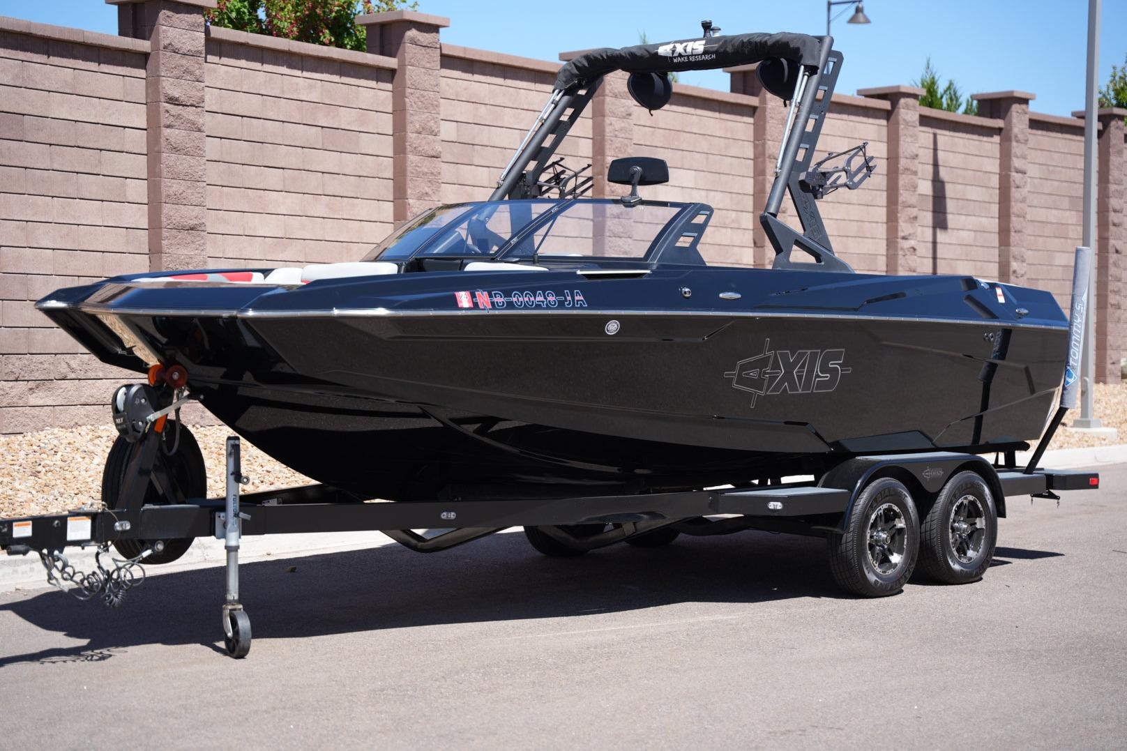 2019 Axis A22 boat on trailer, sleek black design, parked near brick wall.