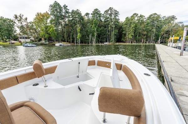 2025 Sea Hunt Ultra 235 SE boat on a serene lake with lush trees.