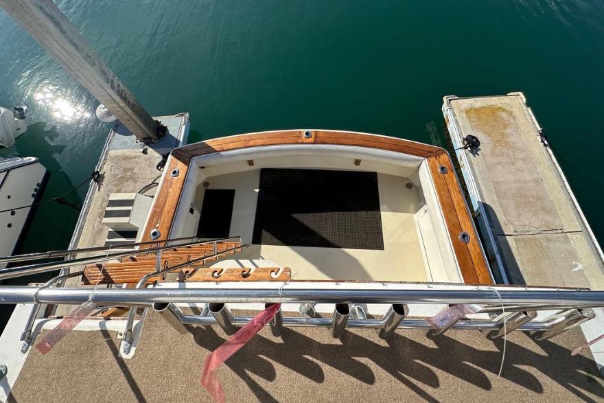 1985 Egg Harbor 33 Sedan boat docked, featuring a wooden deck and stainless steel railings.