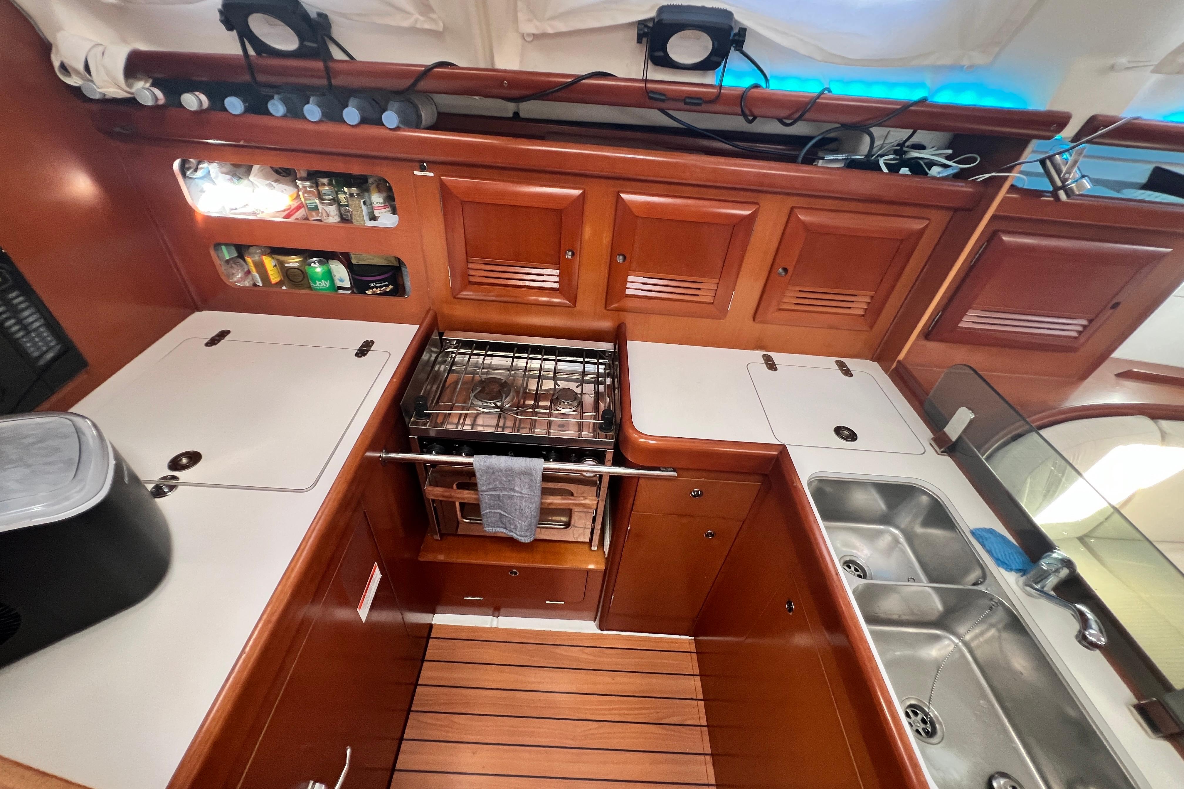 2007 Beneteau 393 yacht kitchen with stove, sink, and wooden cabinetry.