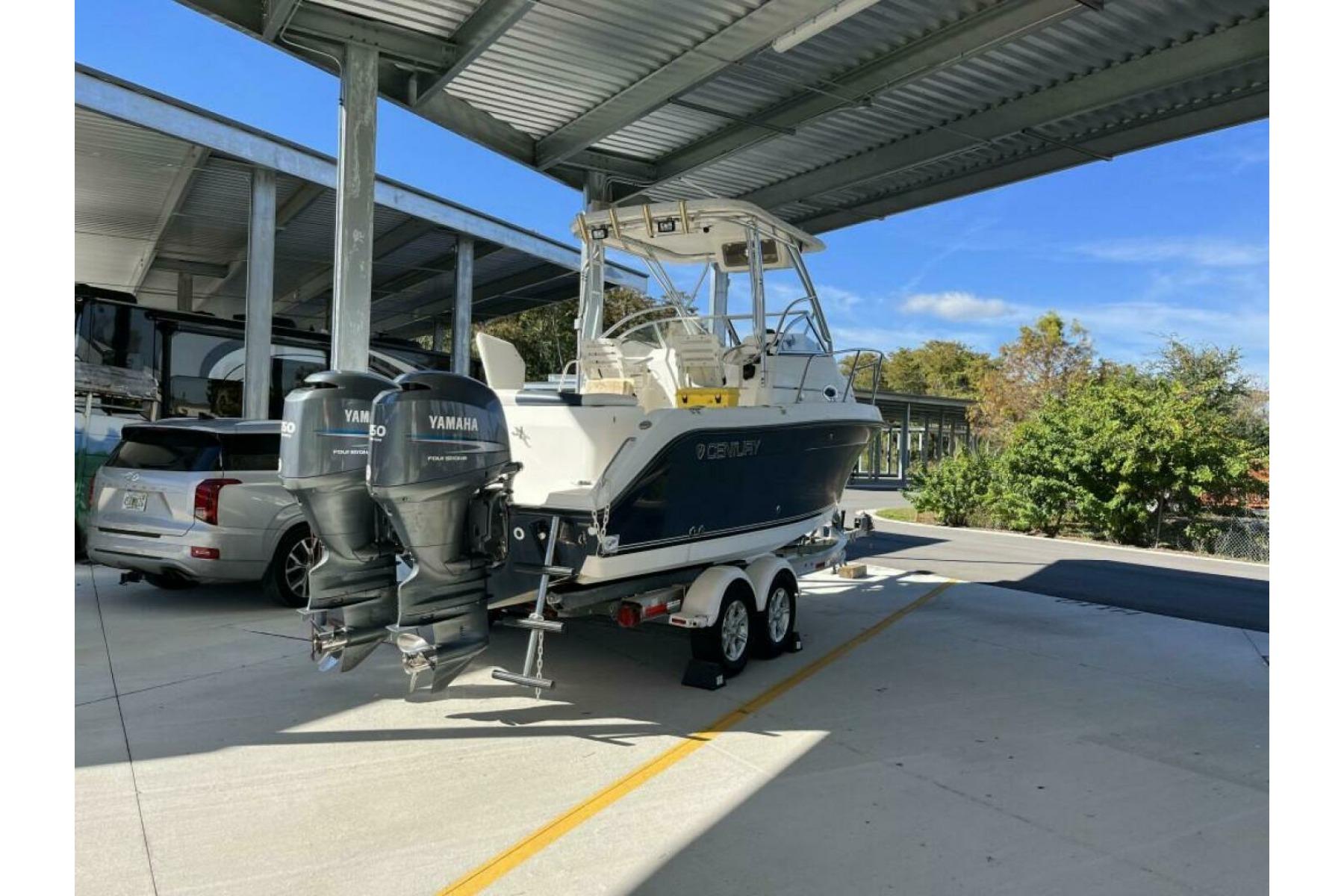 2006 Century 2400 Walk-Around boat with Yamaha engines, parked under a metal canopy.