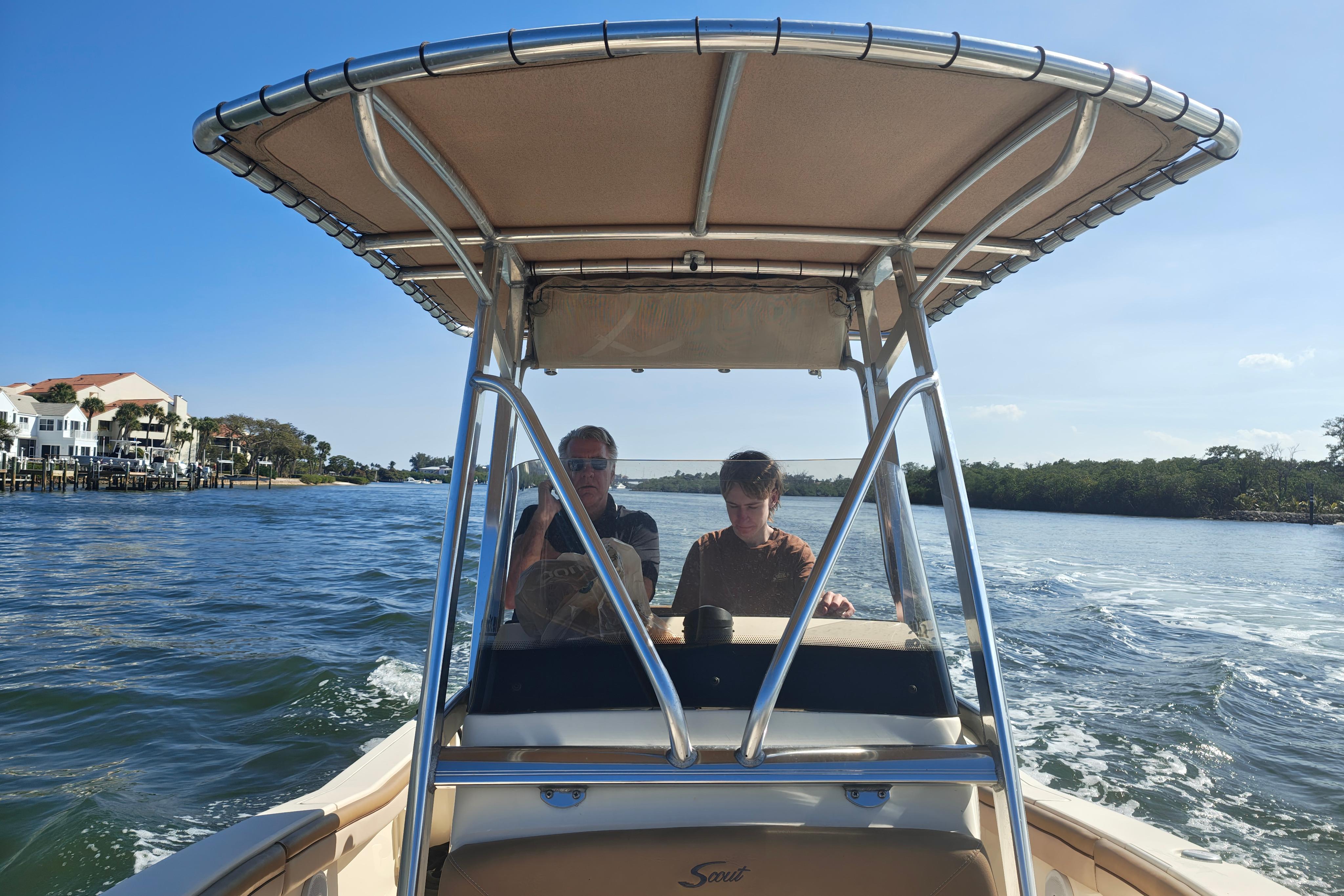 Two people on a 2020 Scout 215 XSF boat cruising on a sunny day.