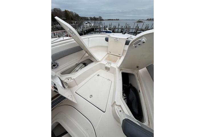 2021 Robalo R242 Explorer boat with open storage compartments, docked by a serene waterfront.