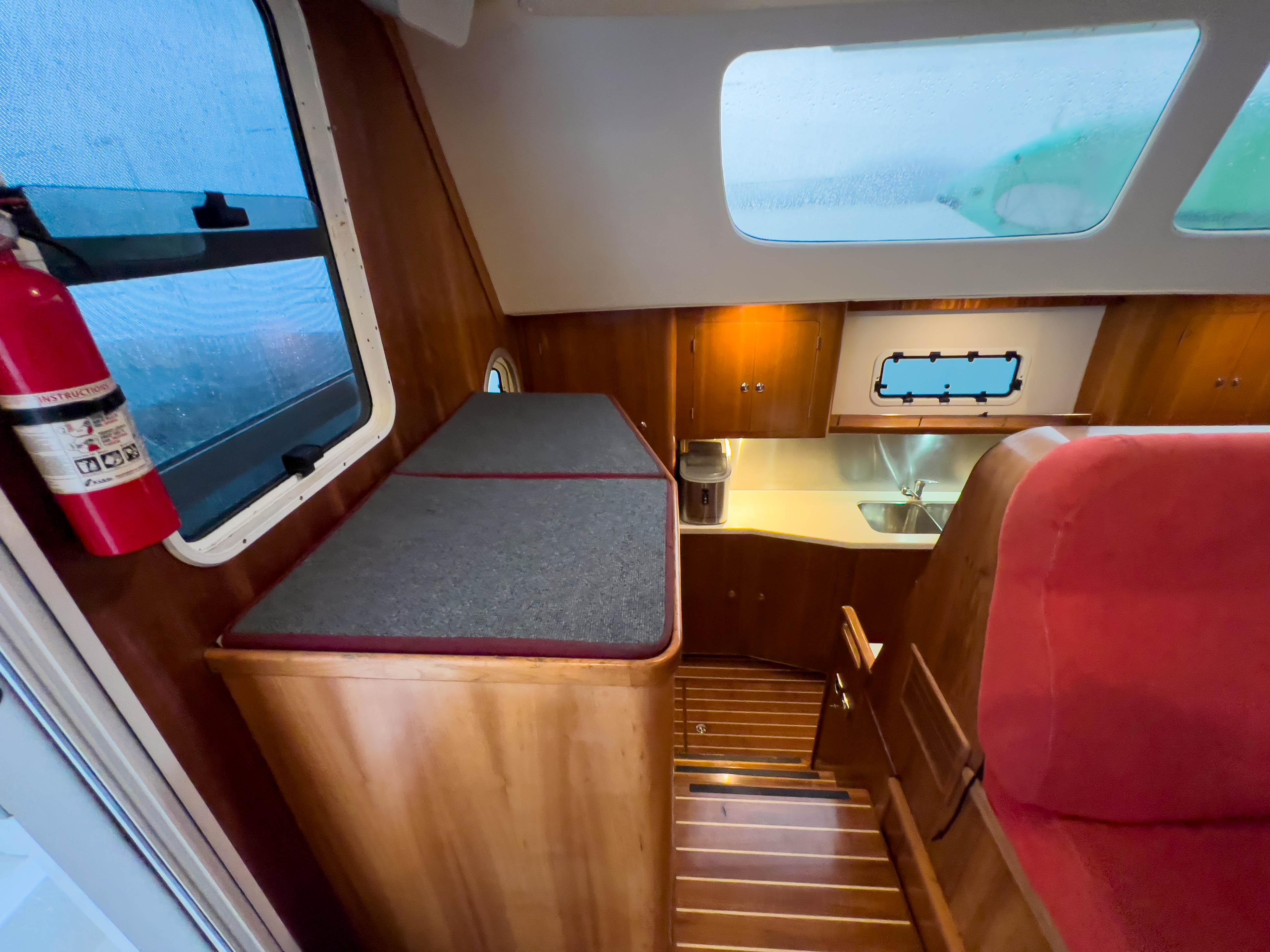 Interior of 2005 Antares PDQ 44 yacht, featuring a compact kitchen and wooden cabinetry.